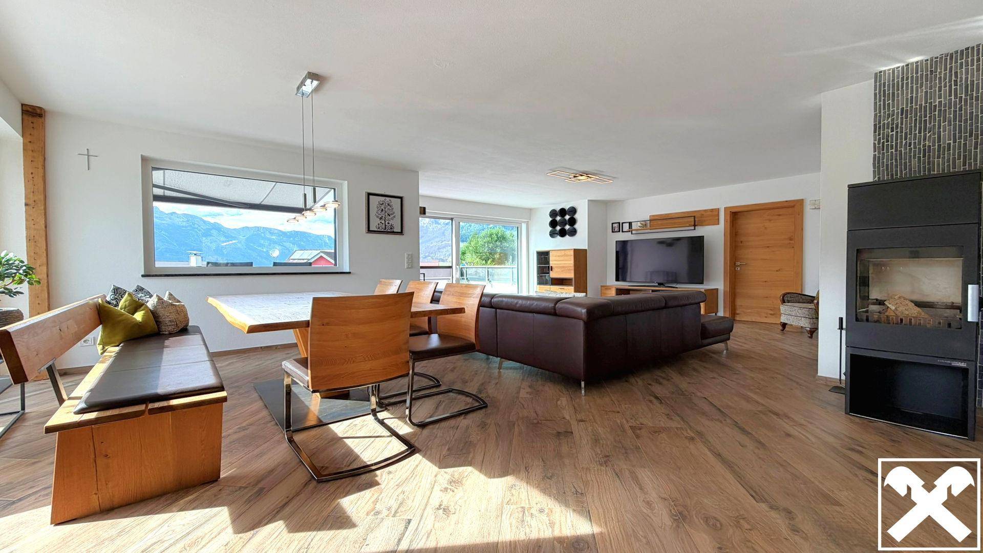 Heller Wohn-Essbereich mit Holzboden, modernem Kamin und Panoramablick auf die Berge.