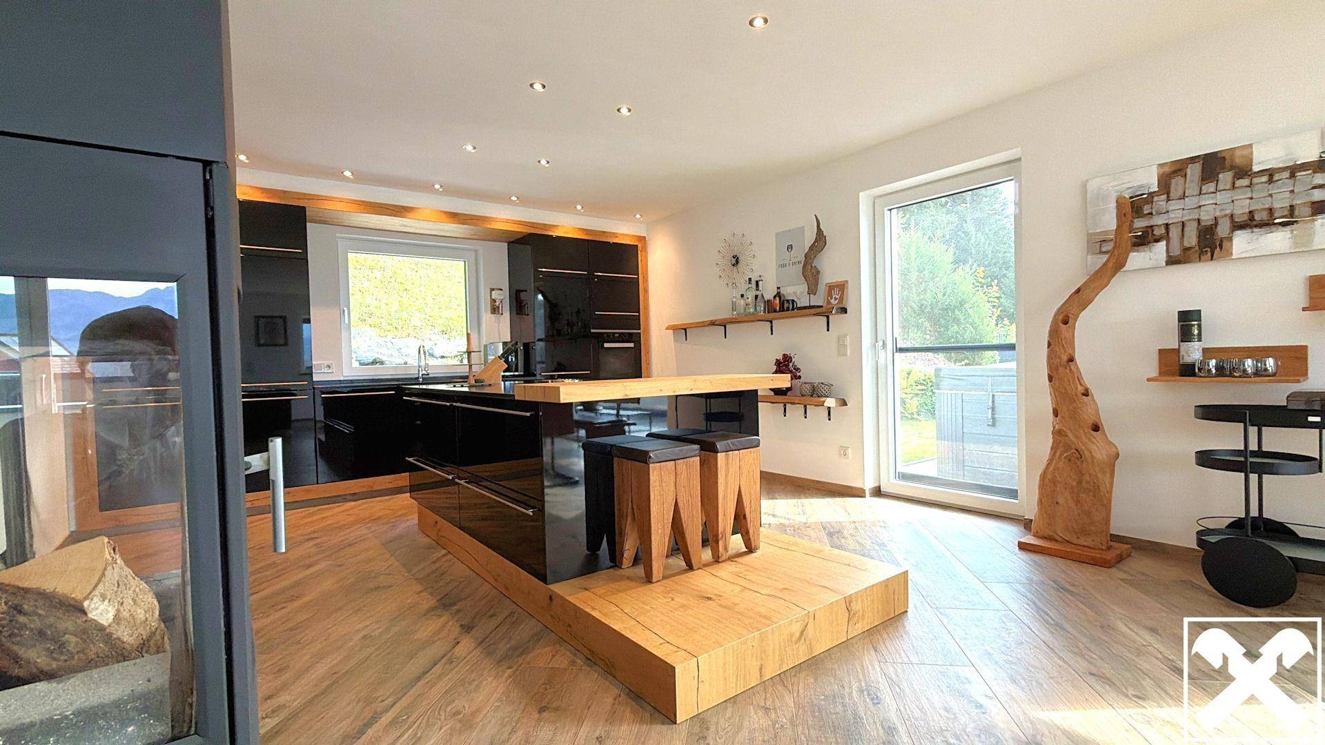 Moderne Küche mit schwarzen Hochglanzfronten, Kücheninsel und Zugang zur Terrasse.