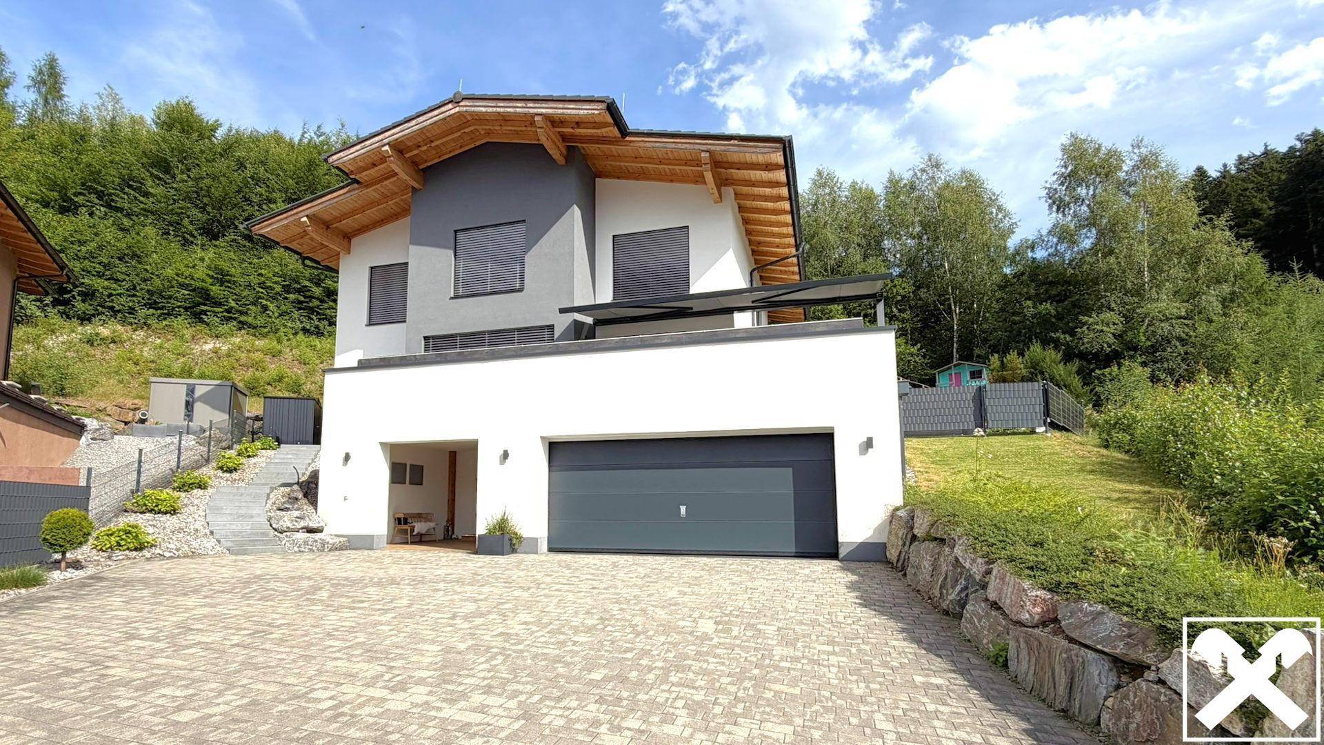 Vorderansicht des modernen Hauses mit gepflasterter Auffahrt und großer Doppelgarage.