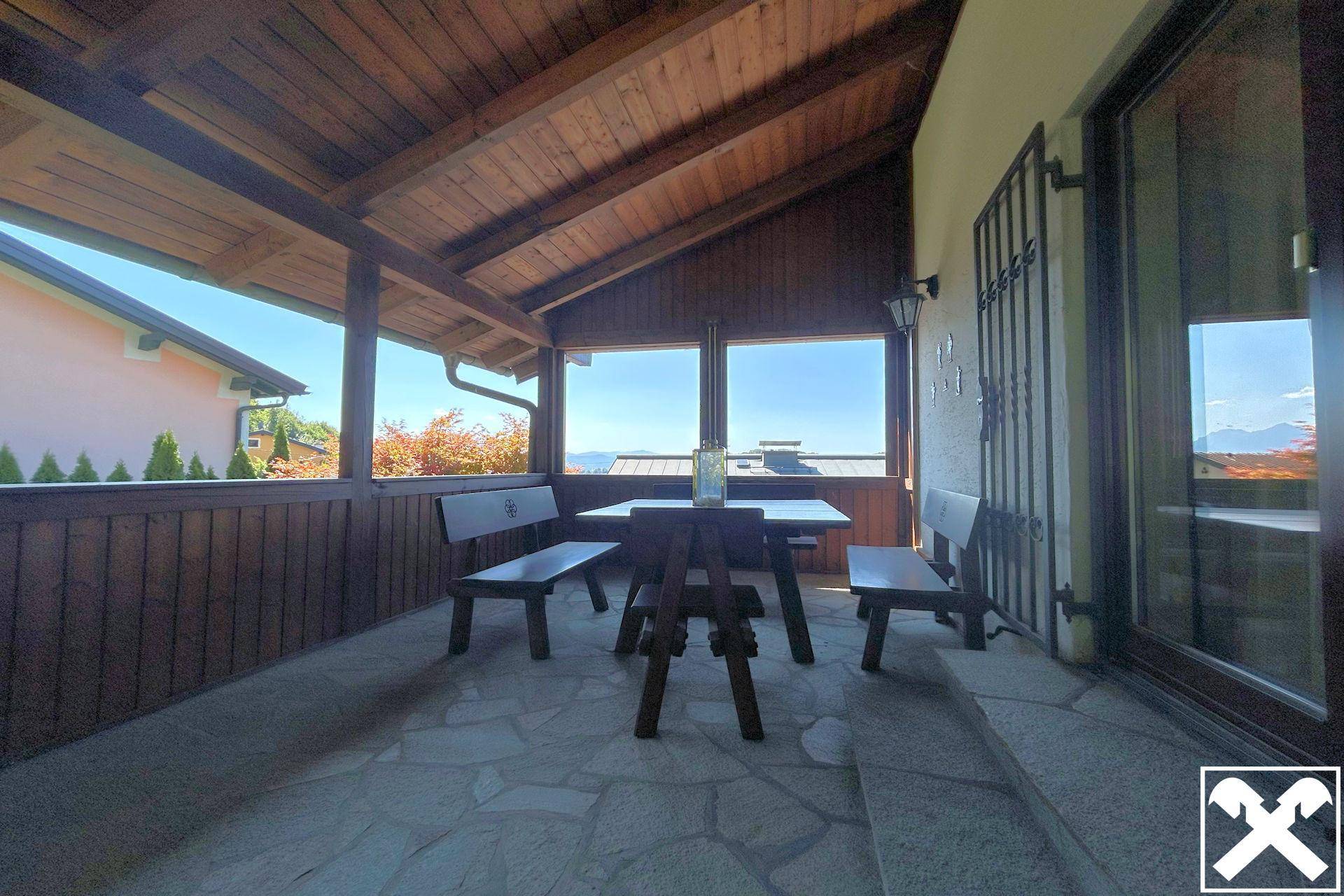Überdachte Terrasse mit Holzbalken und rustikalen Sitzgelegenheiten, ideal für entspannte Stunden im Freien.
