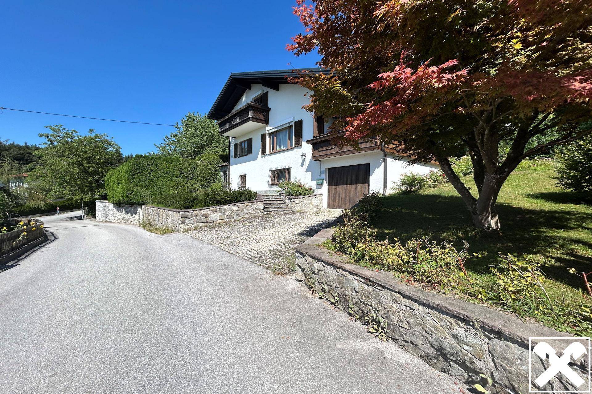 Ansicht des Hauses von der Straße mit gepflasterter Auffahrt und einem roten Ahornbaum im Vorgarten.