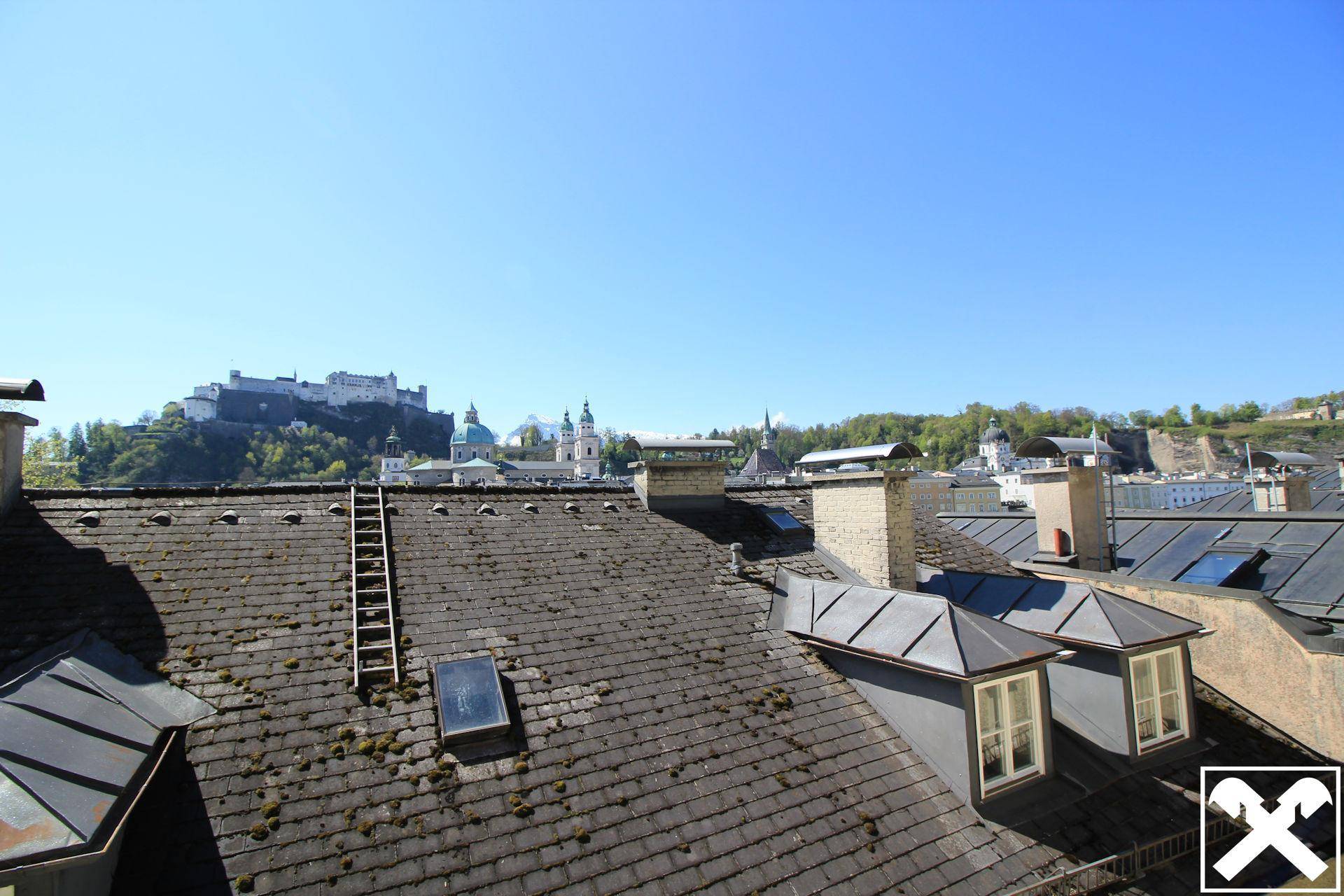 Panoramablick über die Dächer der Stadt Salzburg mit der Festung Hohensalzburg im Hintergrund.