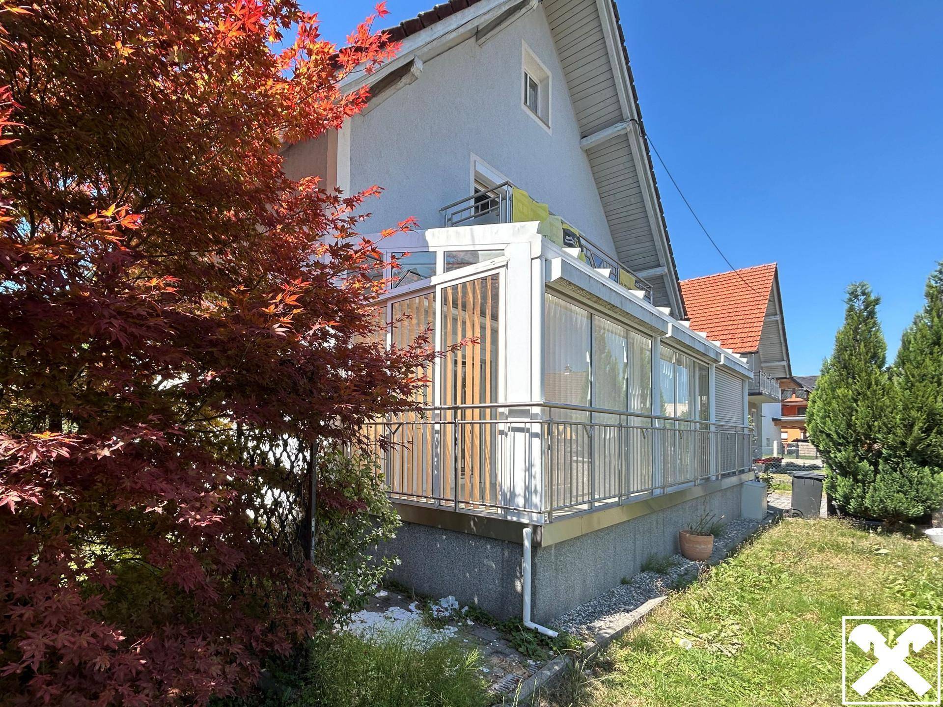 Angebauter Wintergarten mit Glasfronten und Zugang zum Gartenbereich des Hauses.