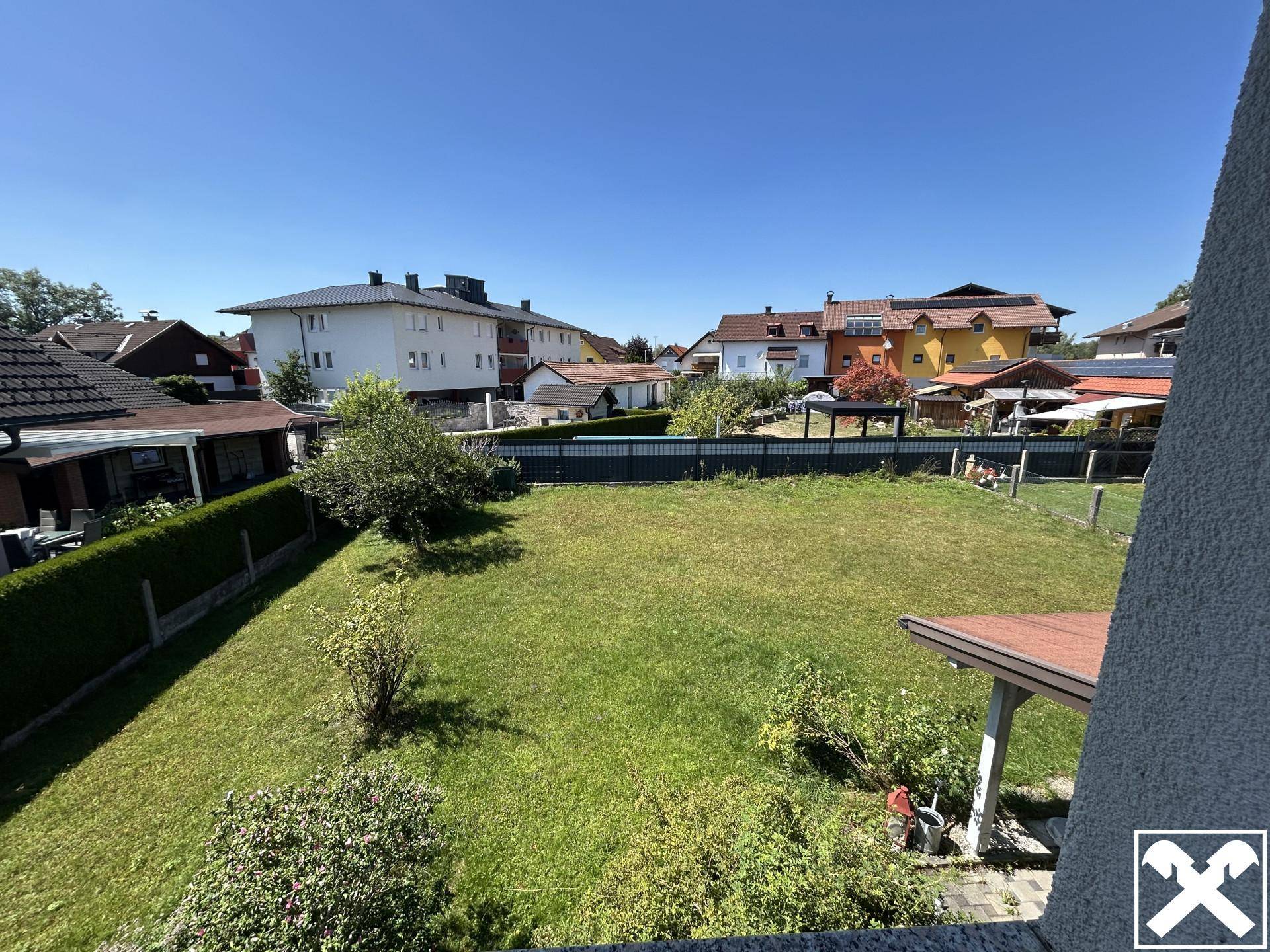 Weitläufiger Blick über die Nachbarschaft mit Gärten und Wohnhäusern an einem sonnigen Tag.