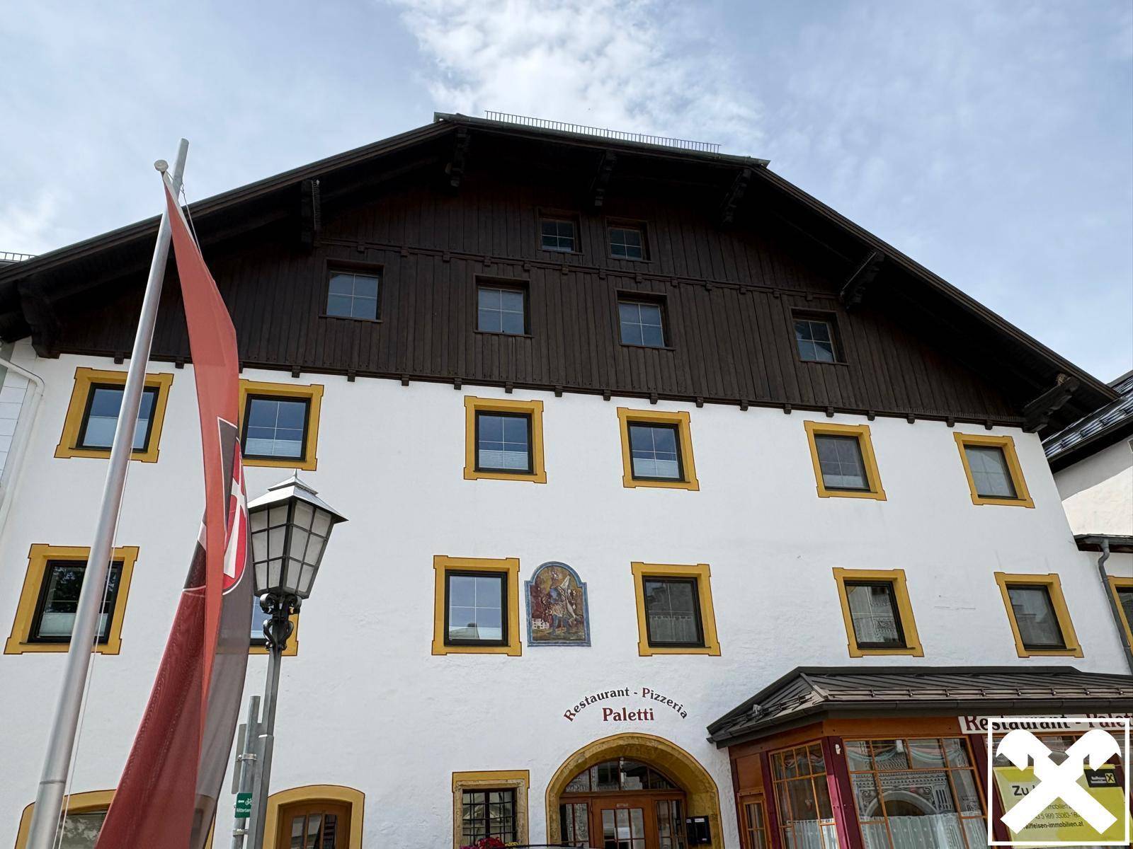 Detailansicht der Fassade eines traditionellen Gebäudes mit Restaurant und Pizzeria im Erdgeschoss.