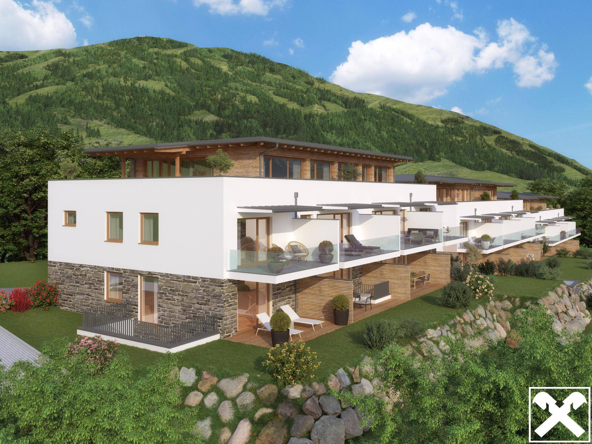 Moderne Wohnanlage mit Terrassen und Balkonen, eingebettet in eine grüne Hügellandschaft mit Bergblick.
