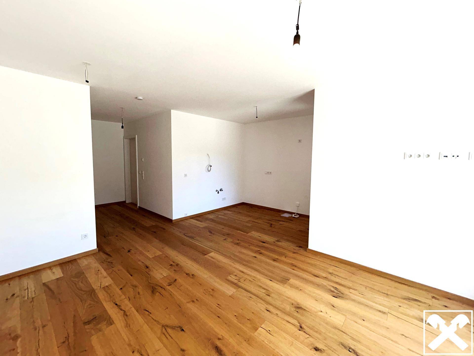 Heller, leerer Raum mit neuem Holzboden und weißen Wänden, bereit für die Einrichtung.