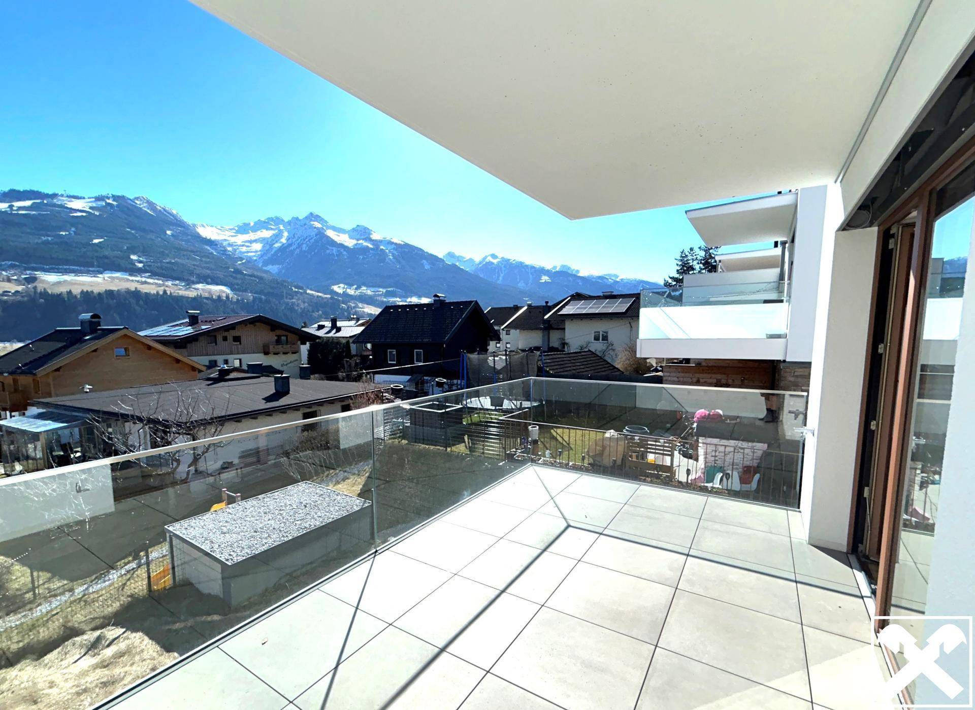 Großer Balkon mit Glasbrüstung und atemberaubendem Panoramablick auf die umliegende Bergwelt.