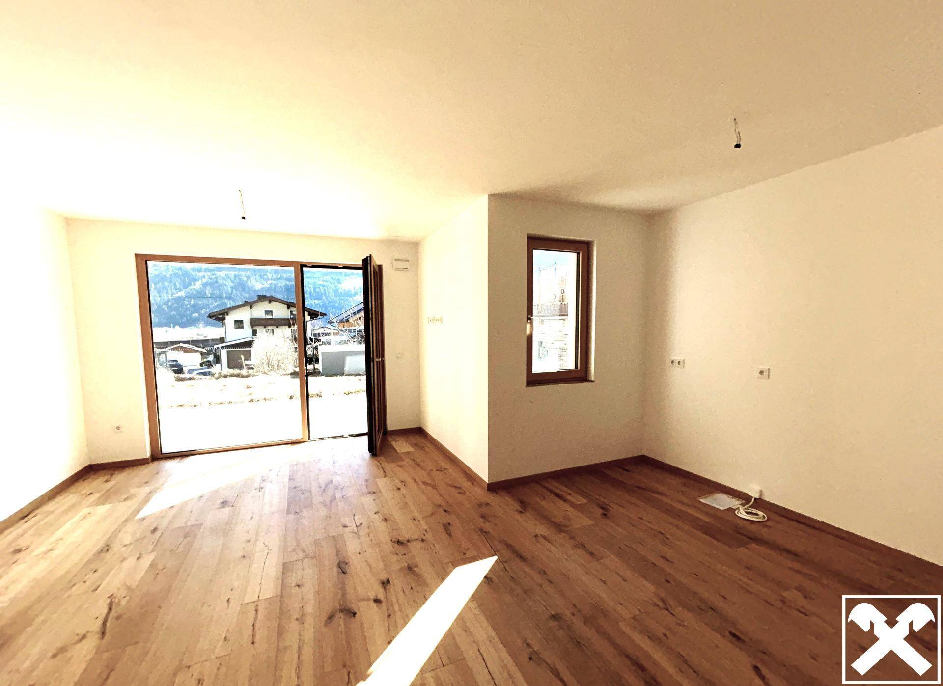 Helles Wohnzimmer mit Holzboden und großen Fenstern, die einen weiten Blick auf die Berge bieten.