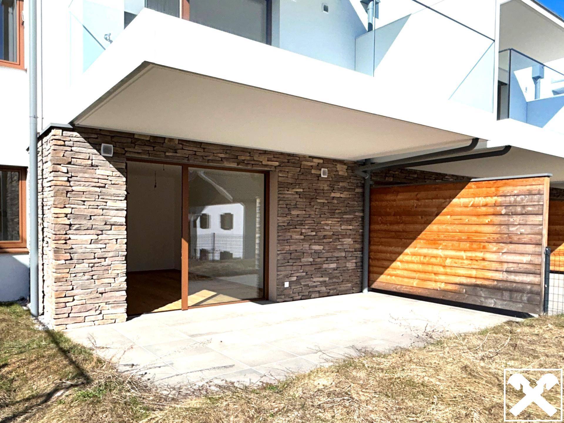 Ebenerdige Terrasse mit Steinverkleidung und Zugang zum Innenbereich, ideal für Entspannung.
