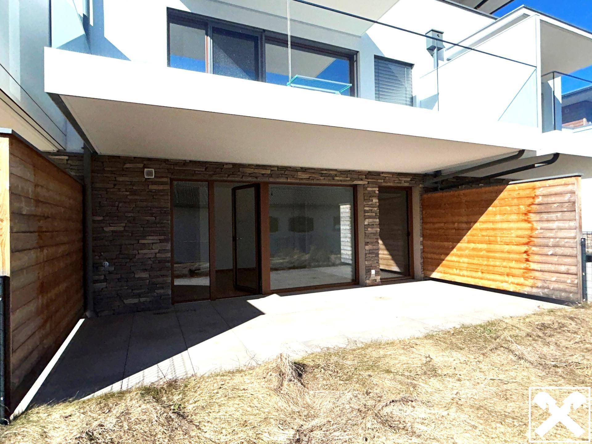 Geräumige Terrasse im Erdgeschoss mit Steinverkleidung und Holzelementen, bereit zur Gestaltung.