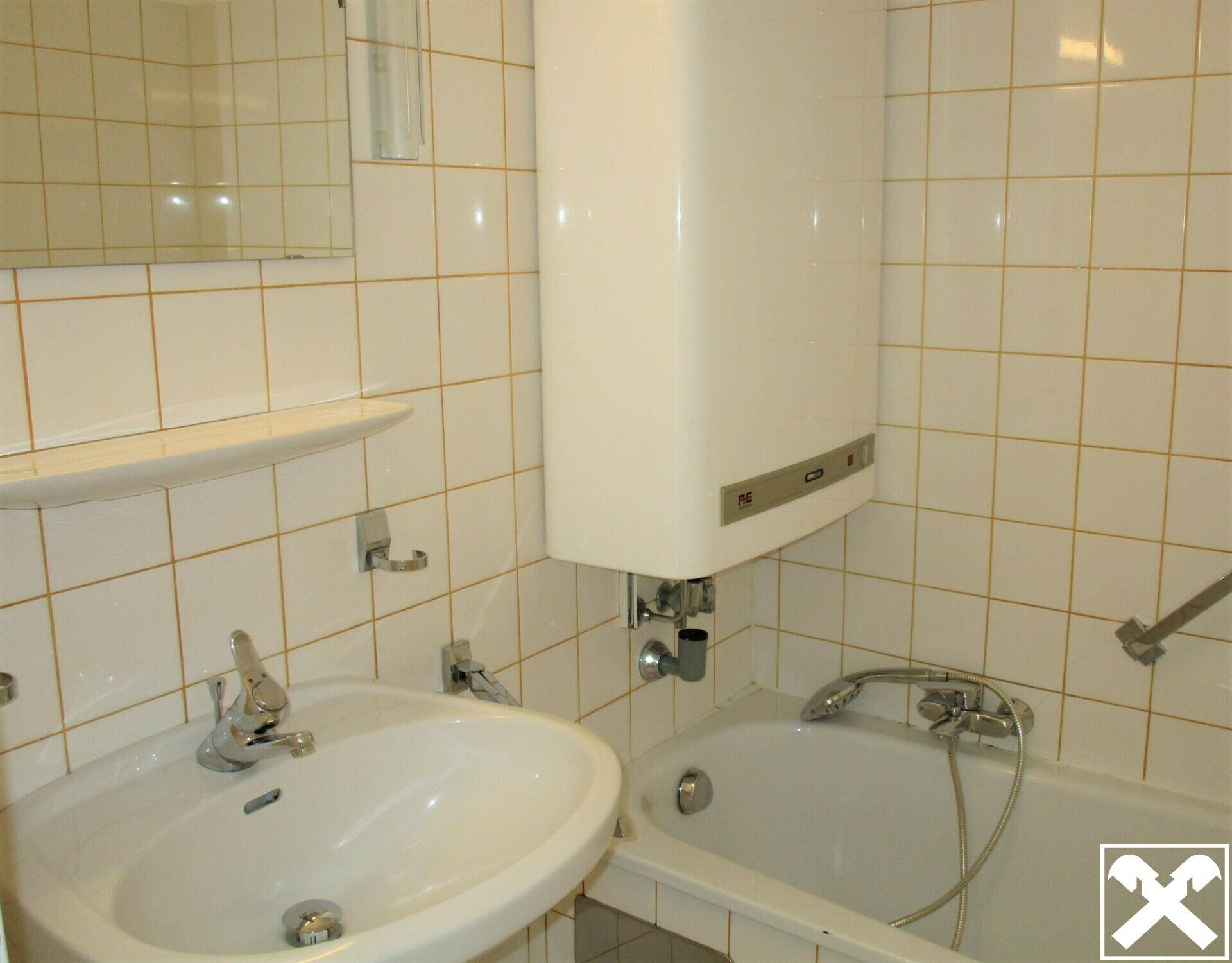 Badezimmer im 80er-Jahre-Stil mit Badewanne, Waschbecken und weißen Fliesen.