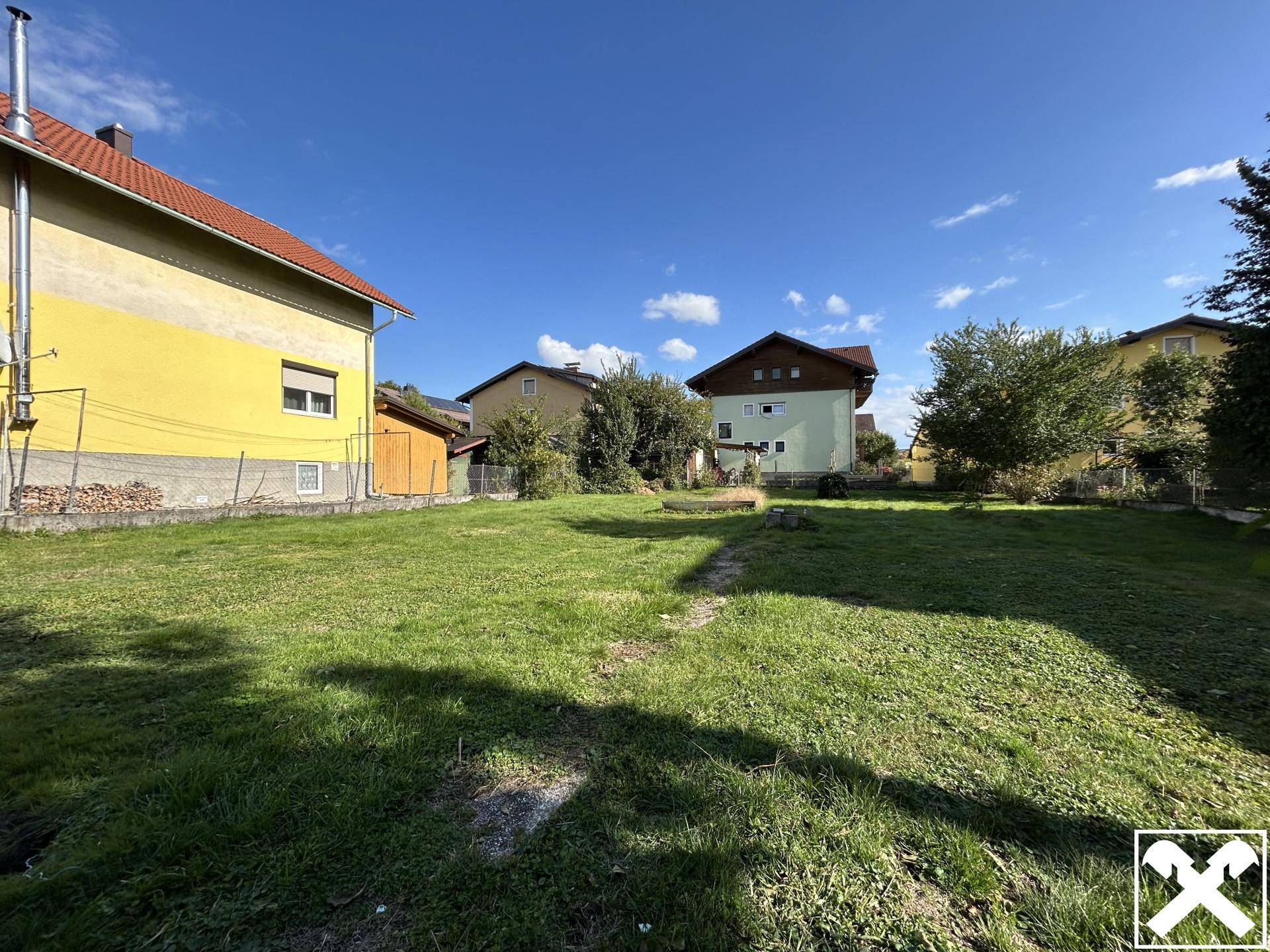 Weitläufiger Gartenbereich mit Rasen und angrenzenden Wohnhäusern unter klarem Himmel.