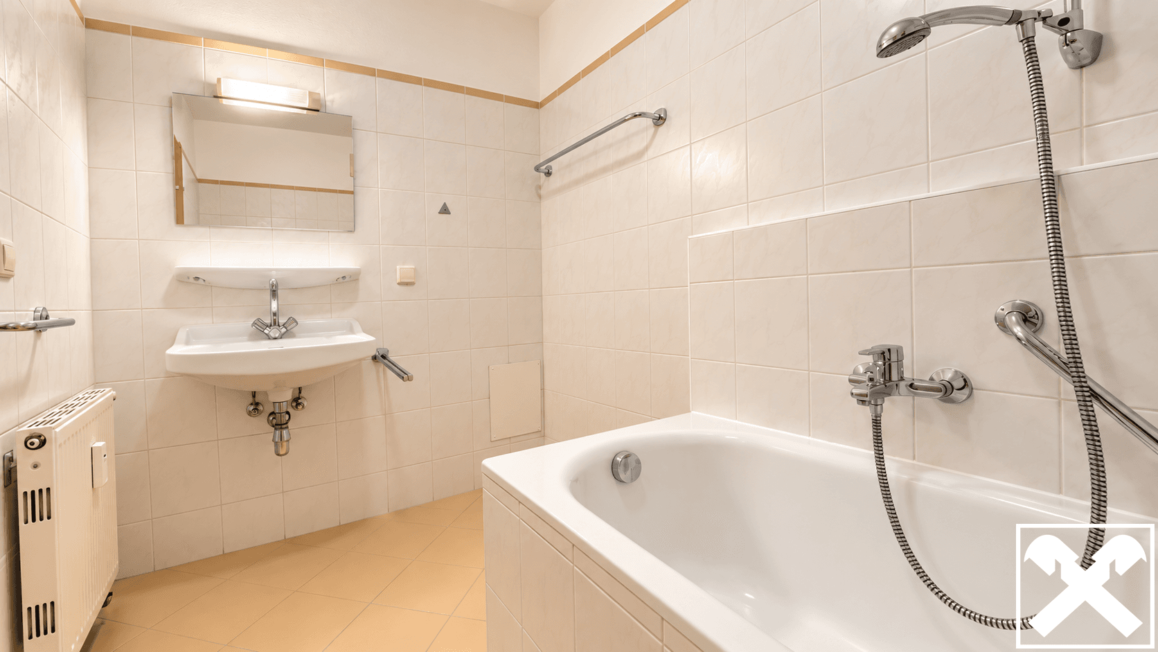 Helles Badezimmer mit Badewanne, Waschbecken und beigen Fliesen in gutem Zustand.