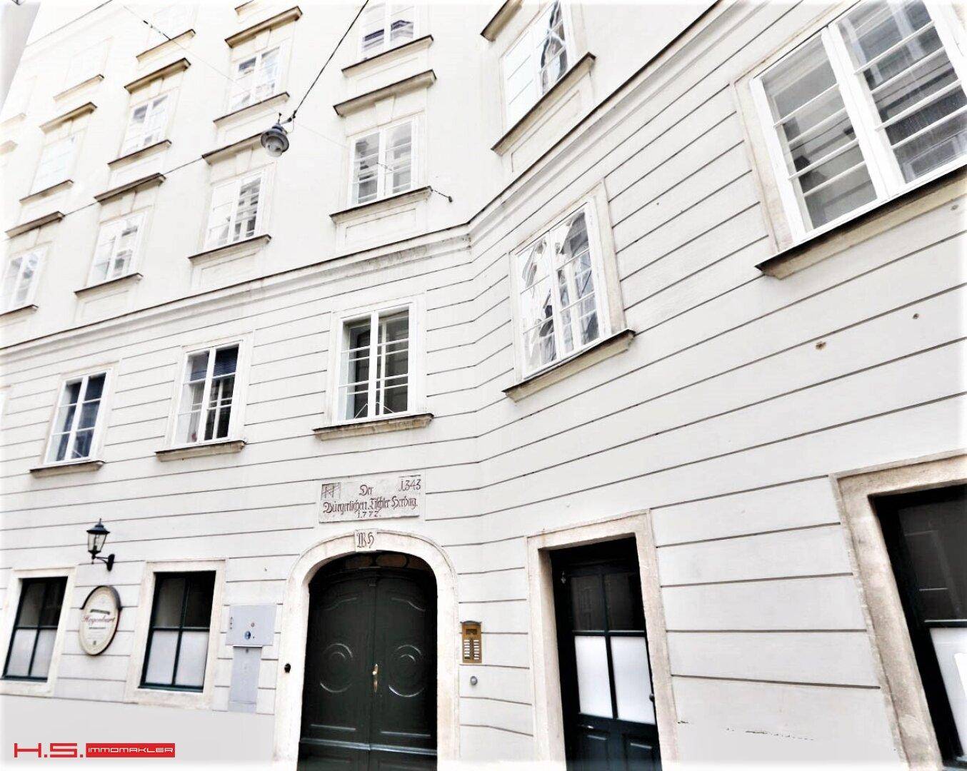 Historische weiße Fassade eines Altbaus mit vielen Fenstern und klassischem Eingangsbereich.