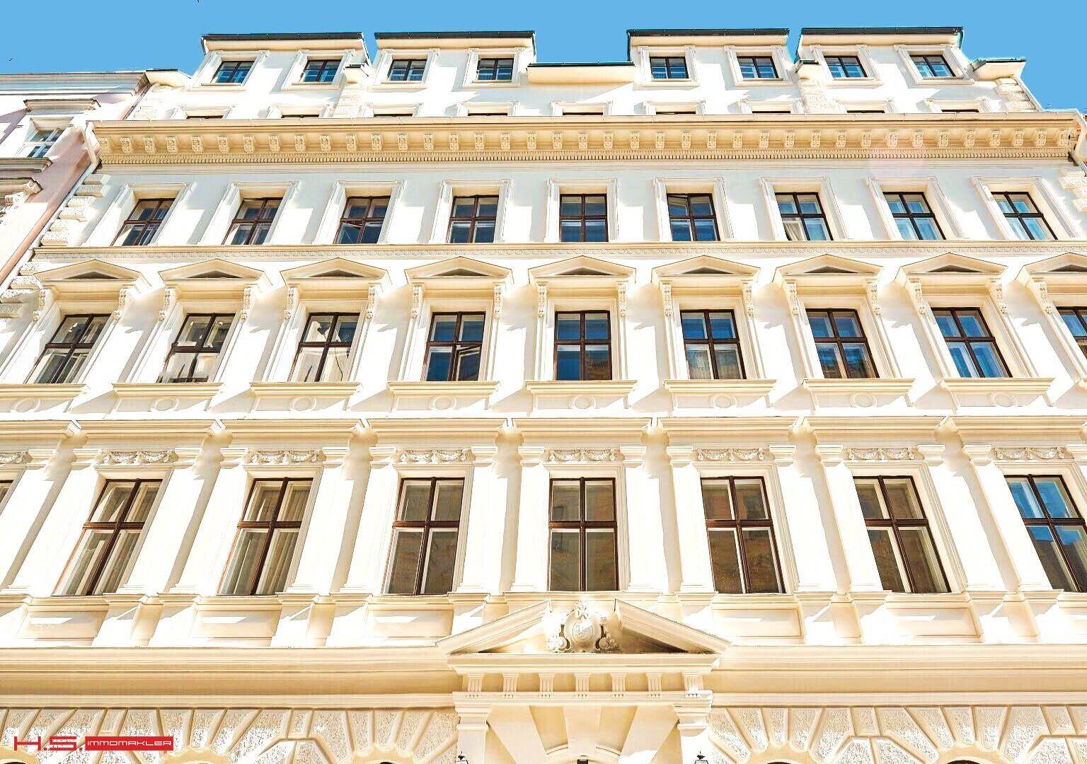 Klassische Fassade eines Altbaus mit vielen Fenstern und dekorativen architektonischen Elementen.