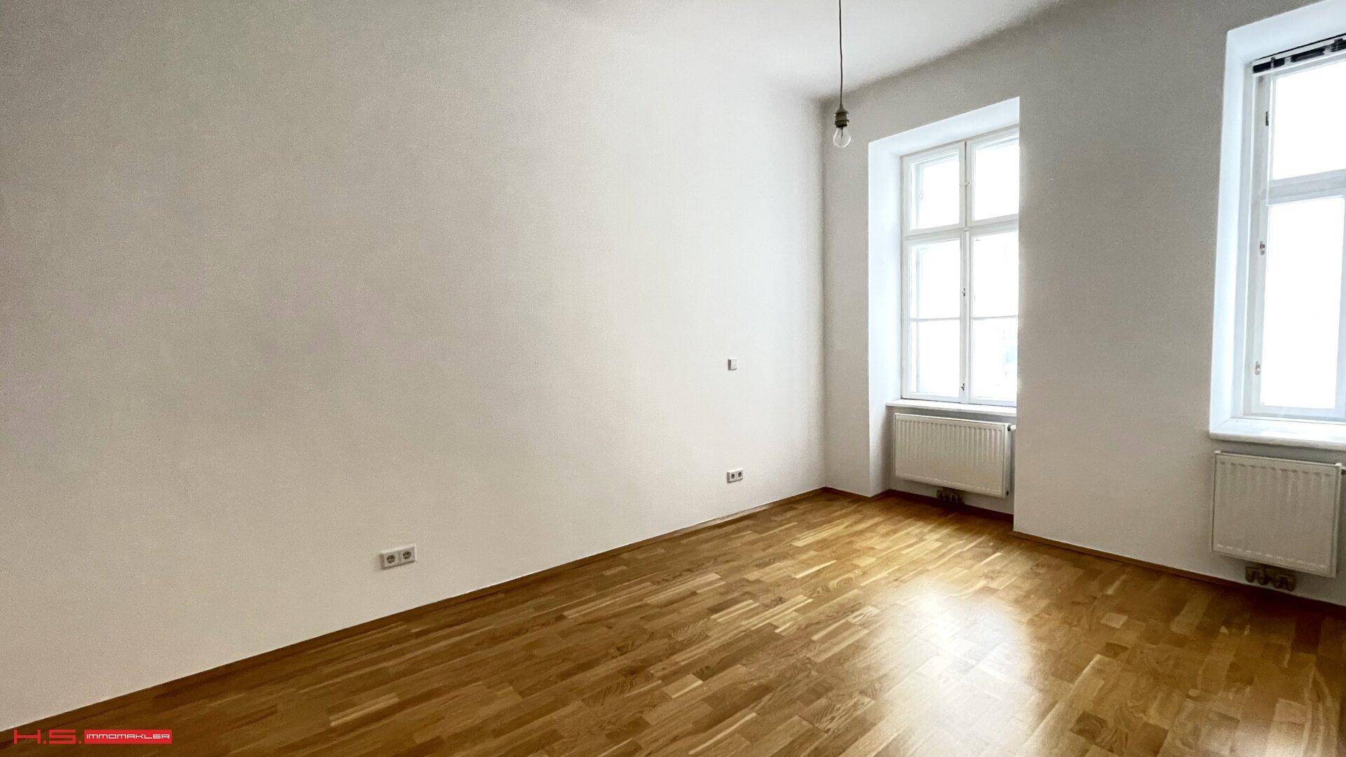 Heller Raum mit Parkettboden und großen Fenstern, bereit zur individuellen Gestaltung.