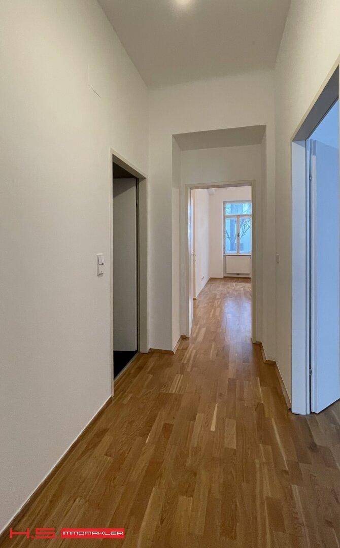 Heller Flur mit Parkettboden, der zu weiteren Räumen der Wohnung führt.