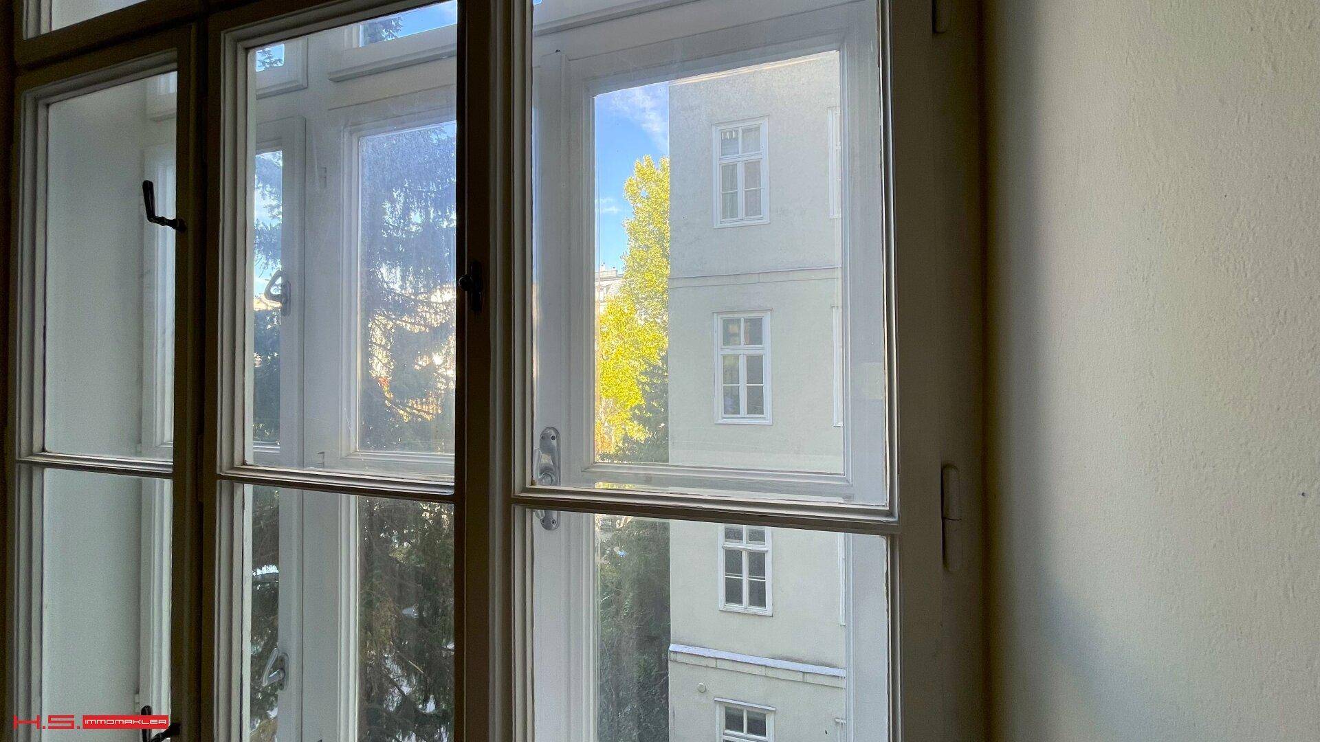 Fenster mit Blick auf die umliegenden Gebäude und grüne Bäume, bietet natürliches Licht.