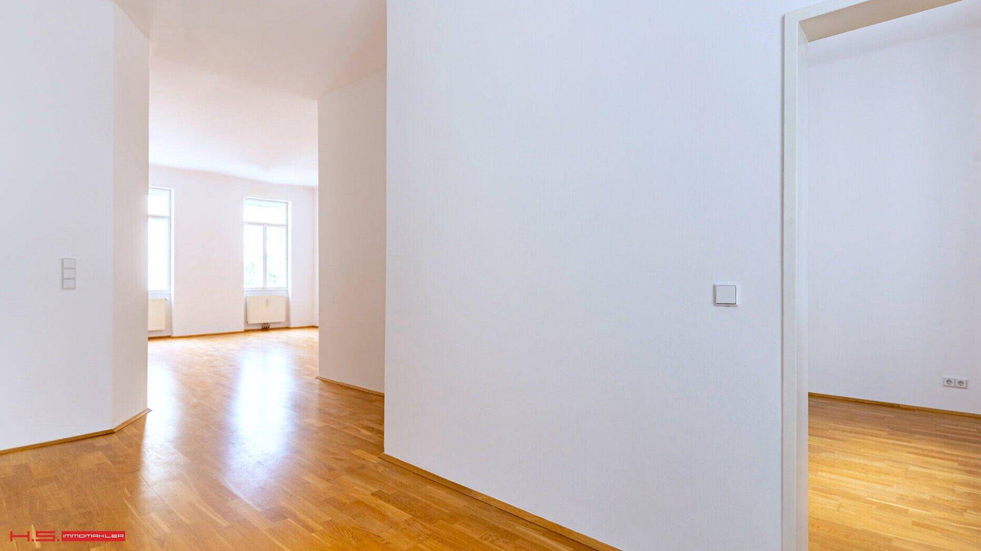 Heller, leerer Raum mit Parkettboden und großen Fenstern, bietet viel natürliches Licht.