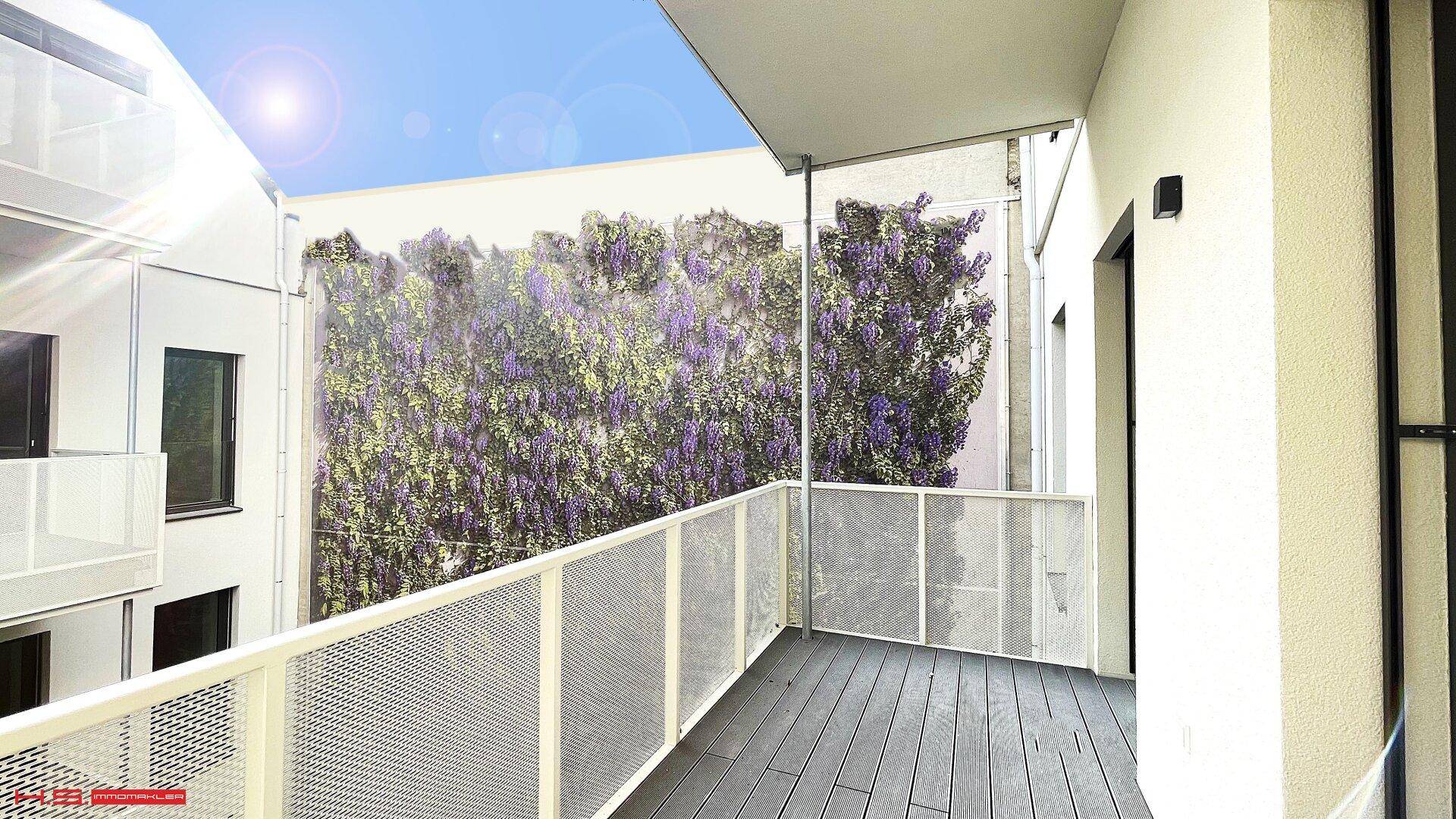 Geräumiger Balkon mit Holzdielenboden und Blick auf eine begrünte Wand, ideal zum Entspannen im Freien.