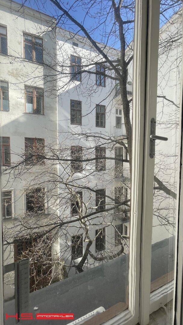 Blick aus dem Fenster auf den Innenhof und die umliegenden Gebäude mit kahlen Bäumen.