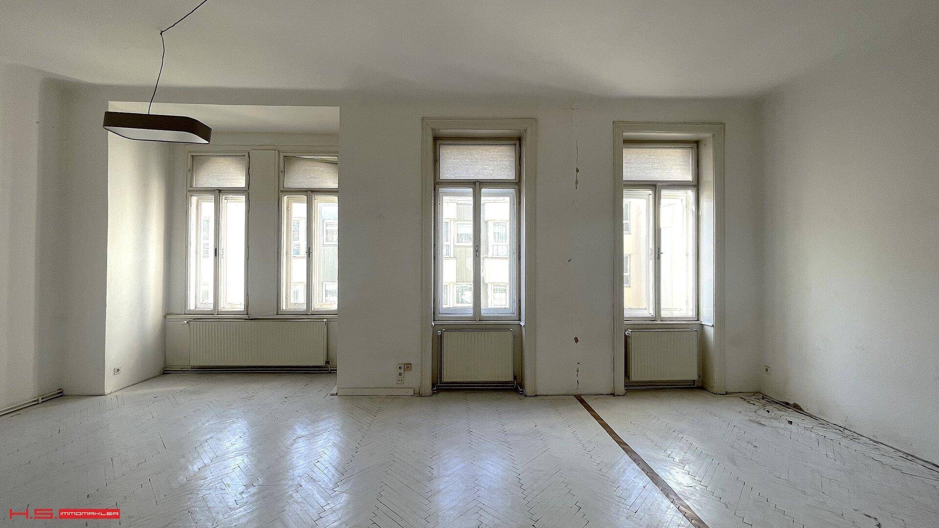Lichtdurchfluteter Wohnraum mit mehreren hohen Fenstern und Blick auf die Umgebung.