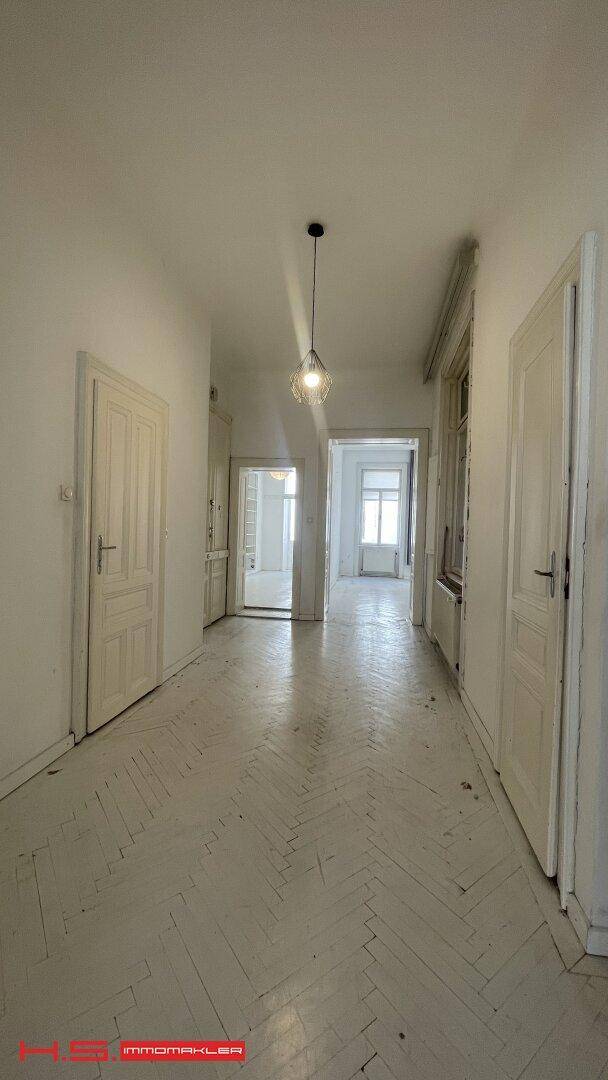Heller und geräumiger Flur mit Fischgrätparkett und Blick in angrenzende Zimmer.