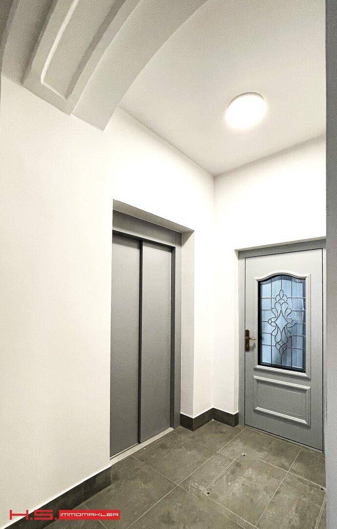 Heller Flur mit modernem Aufzug und einer eleganten Eingangstür.