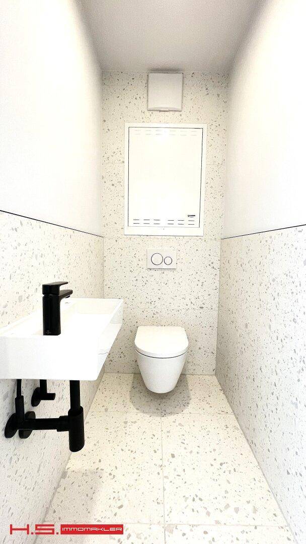 Modernes Gäste-WC mit wandhängender Toilette und kleinem Waschbecken.