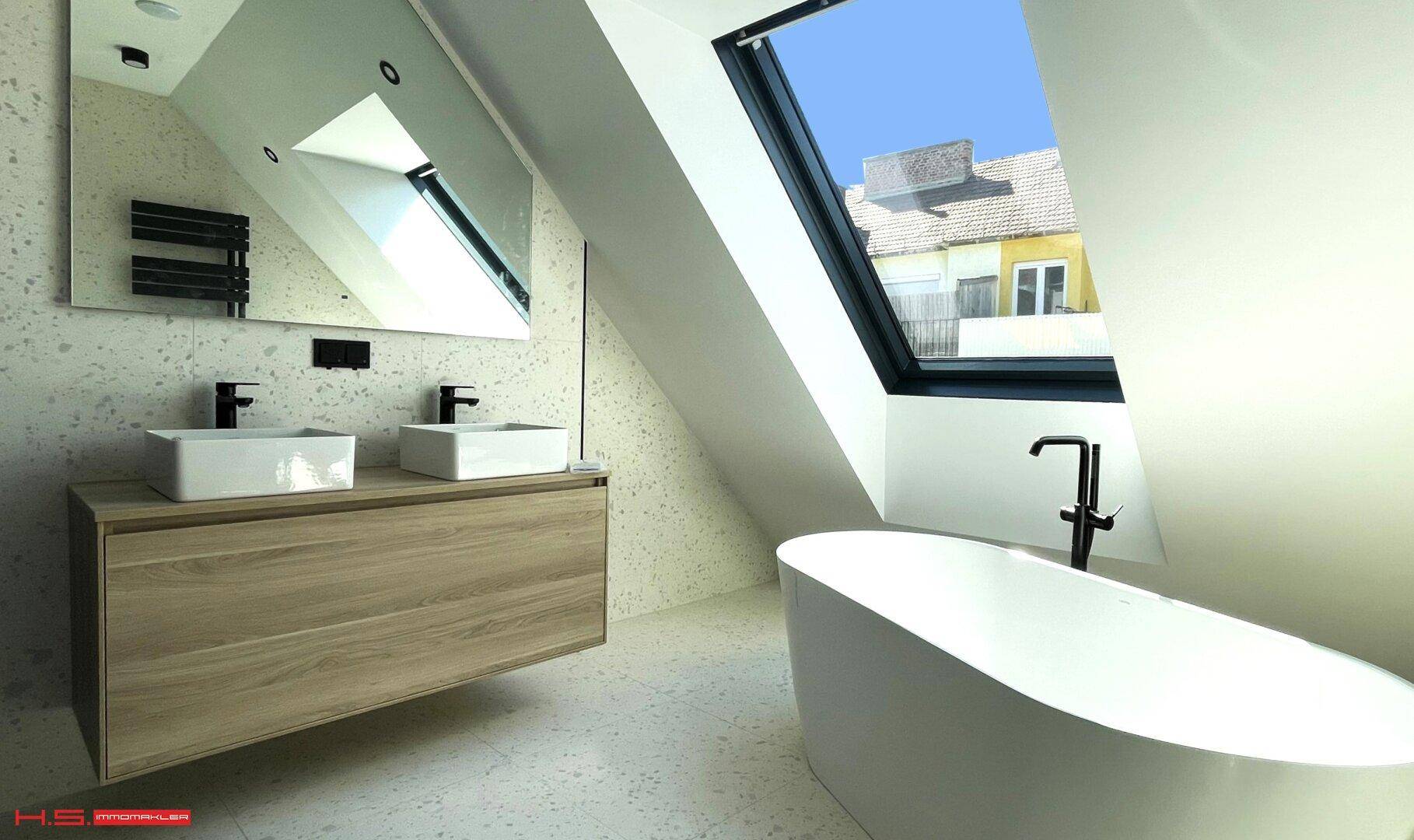 Modernes Badezimmer mit Doppelwaschbecken, freistehender Badewanne und Dachfenster.