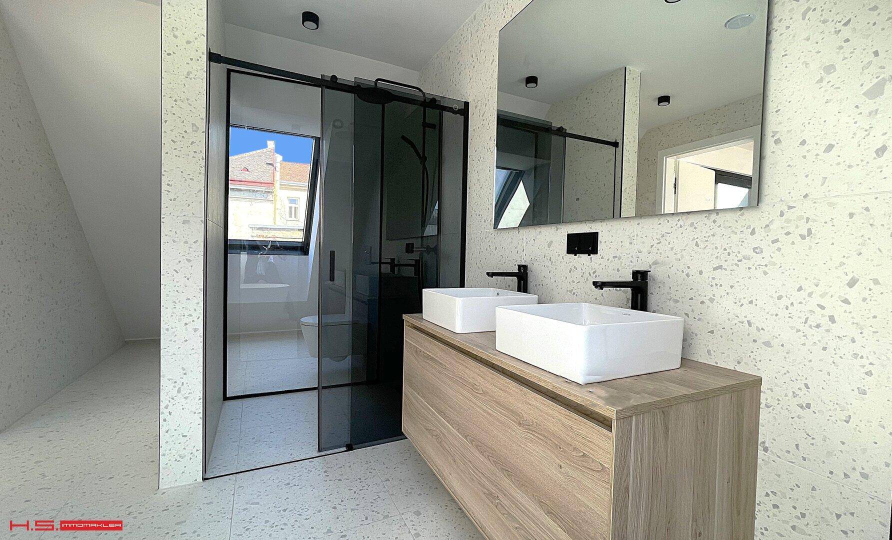 Helles Badezimmer mit Doppelwaschbecken, großer Duschkabine und modernen Fliesen.