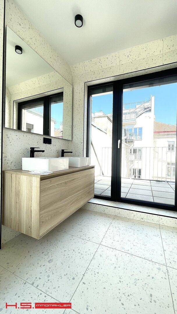 Modernes Badezimmer mit Doppelwaschbecken, großem Spiegel und Zugang zu einem Balkon.