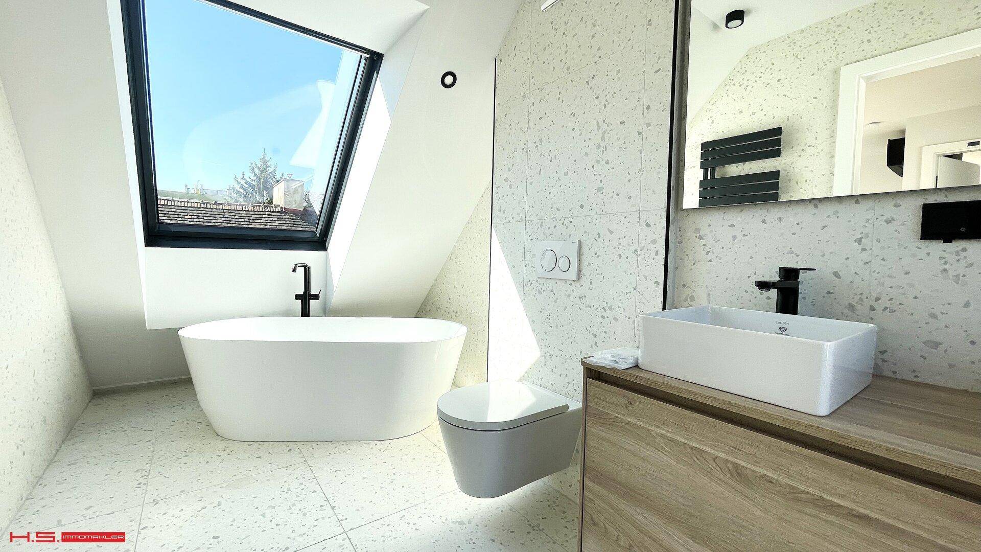 Elegantes Badezimmer mit freistehender Badewanne, Dachfenster und modernem Design.