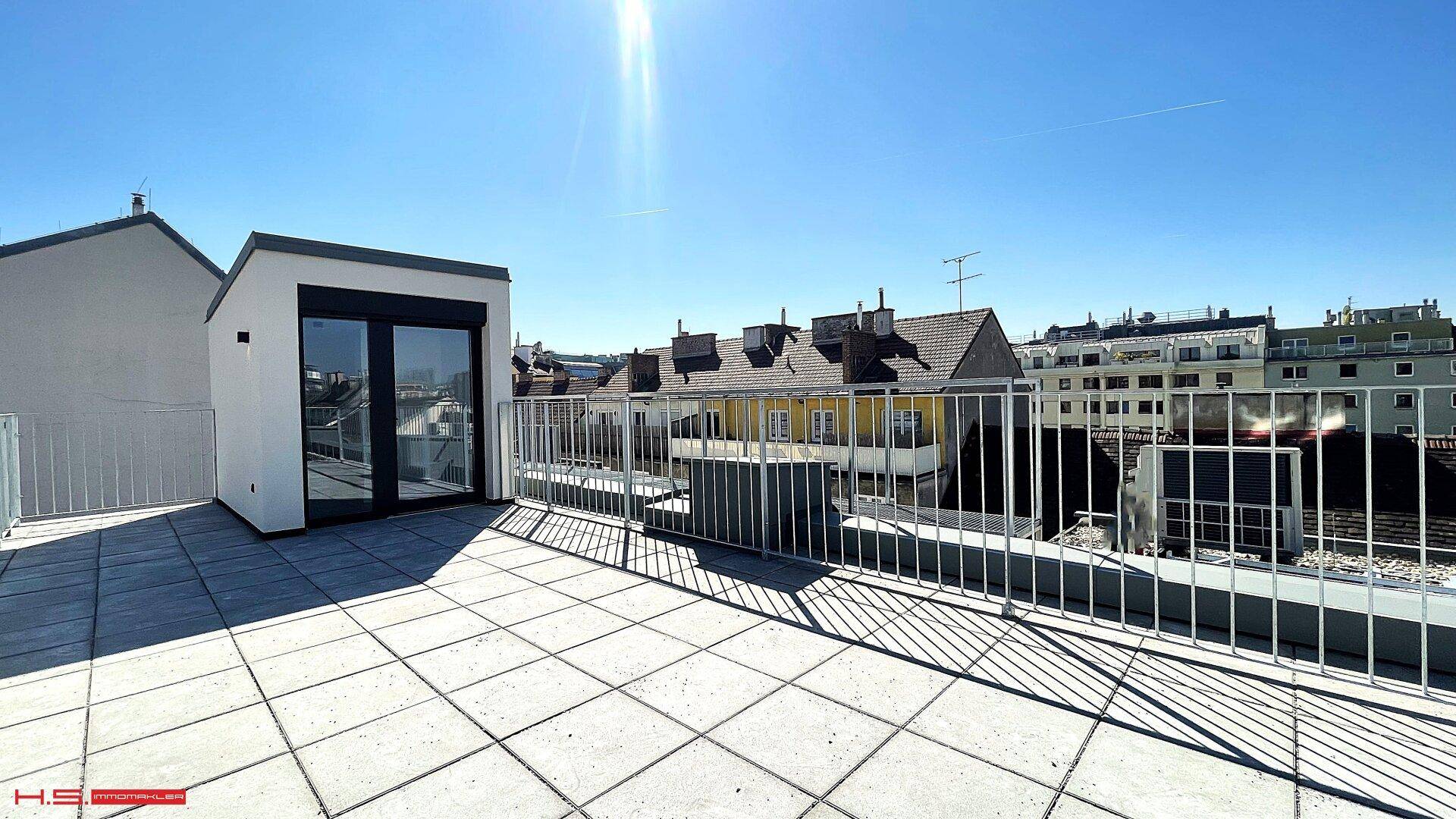 Geräumige Dachterrasse mit Fliesenboden und weitem Blick über die umliegenden Dächer der Stadt.