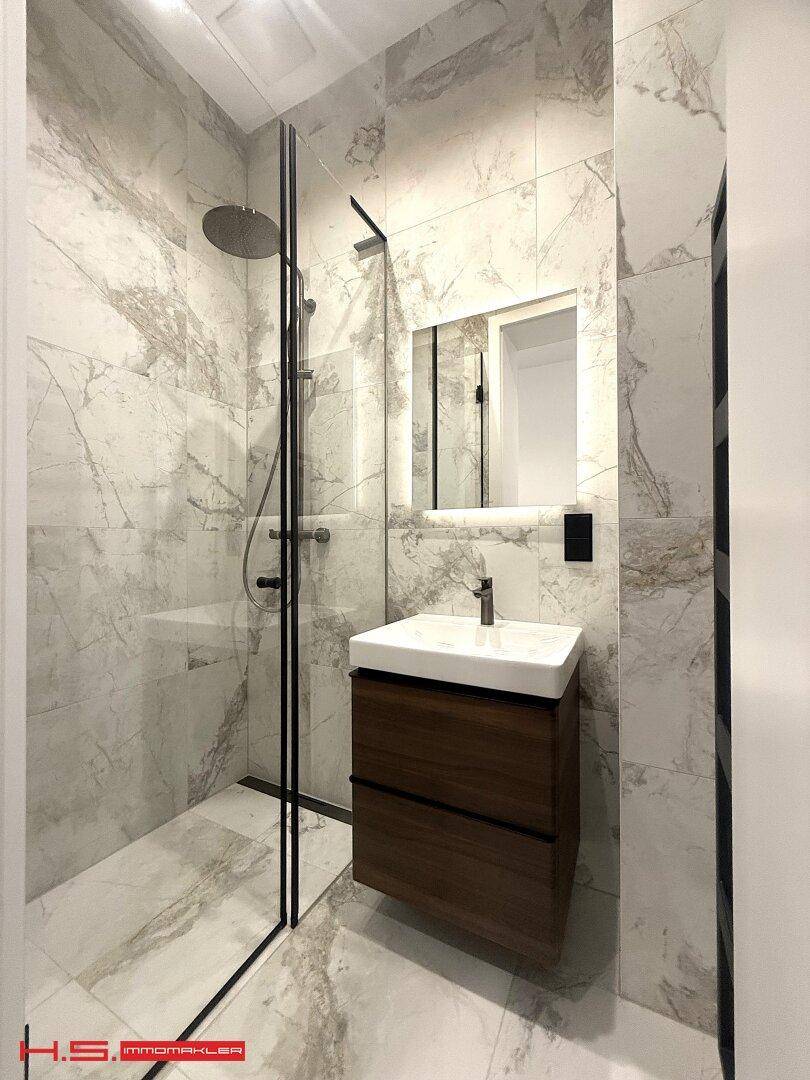 Modernes Badezimmer mit Marmorfliesen, Einzelwaschbecken und ebenerdiger Dusche.