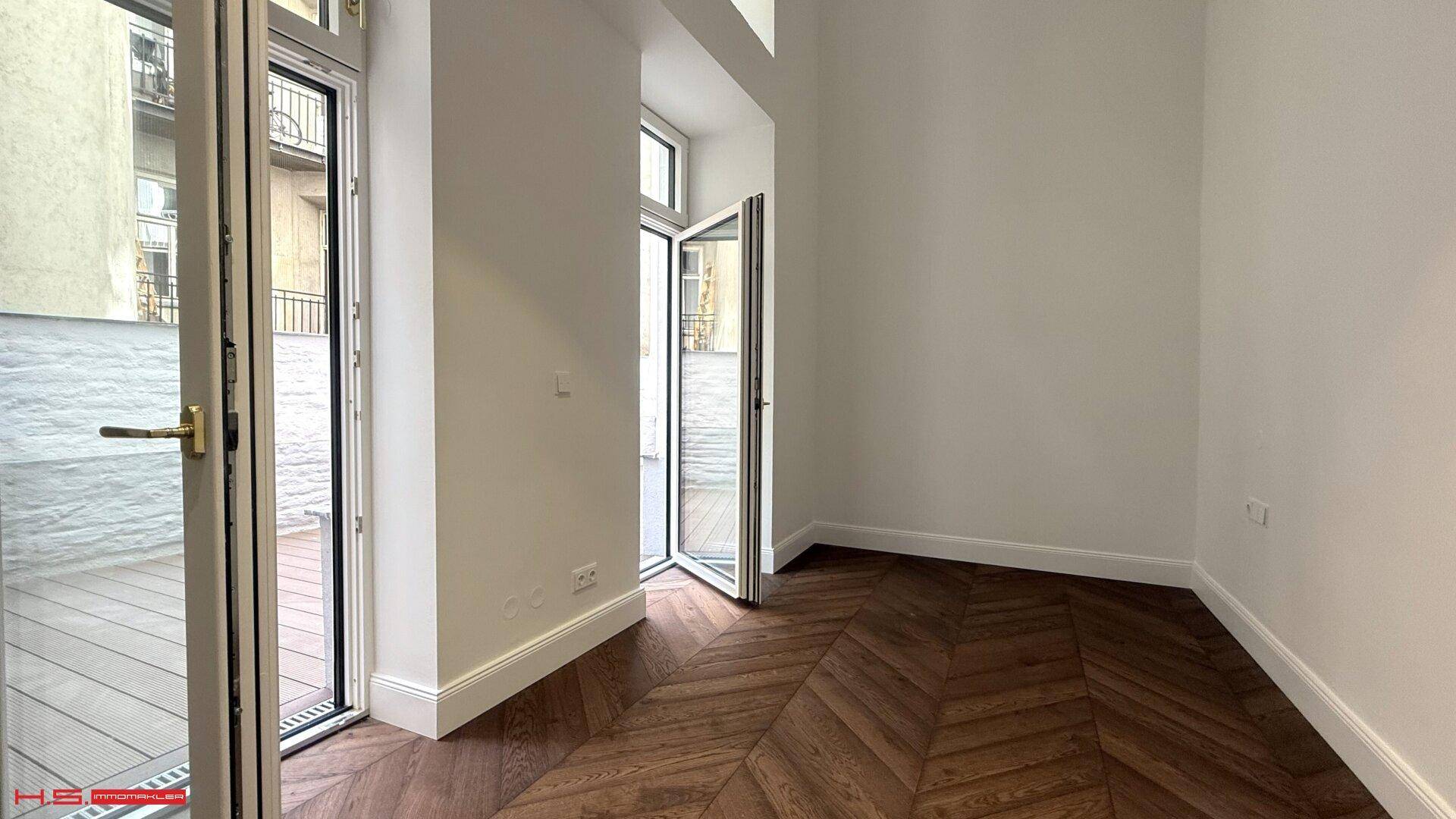 Offene Terrassentüren führen zu einem Außenbereich mit Holzboden.