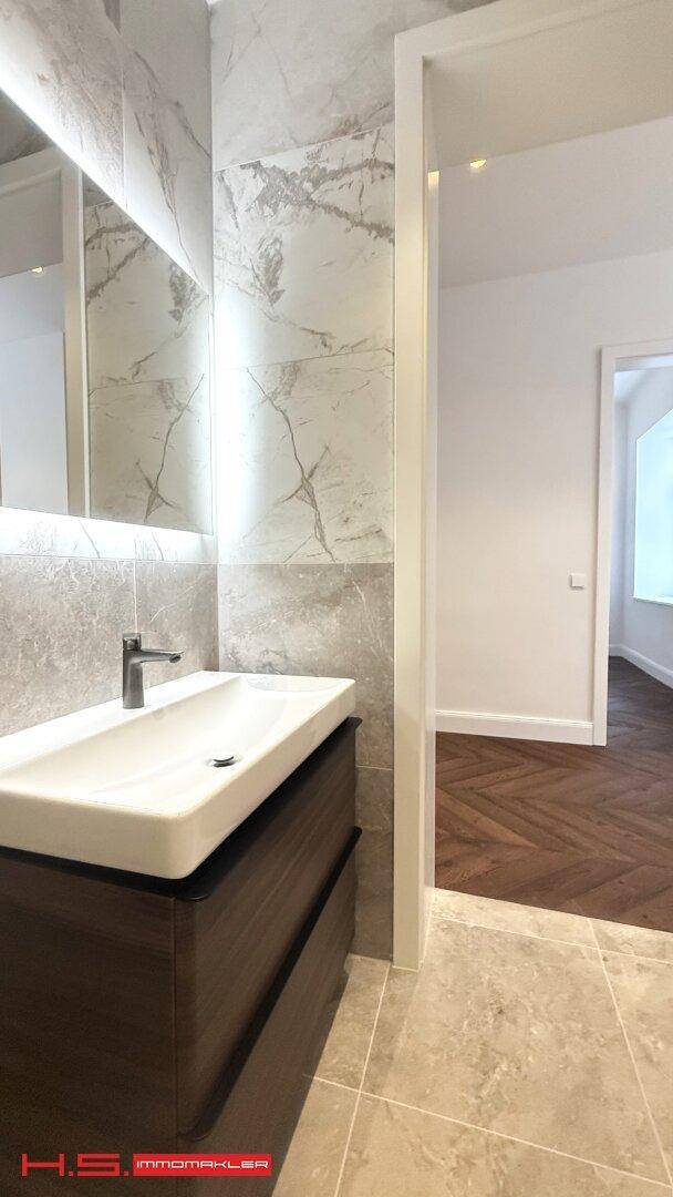 Elegantes Waschbecken mit Unterschrank und beleuchtetem Spiegel in einem modernen Badezimmer, das Stil und Funktion vereint.