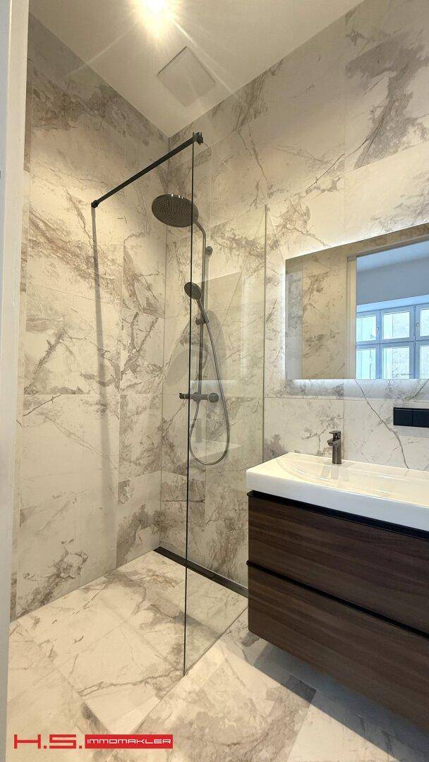 Moderne begehbare Dusche mit Regenduschkopf und eleganten Marmorfliesen im Badezimmer, für ein Spa-Erlebnis.