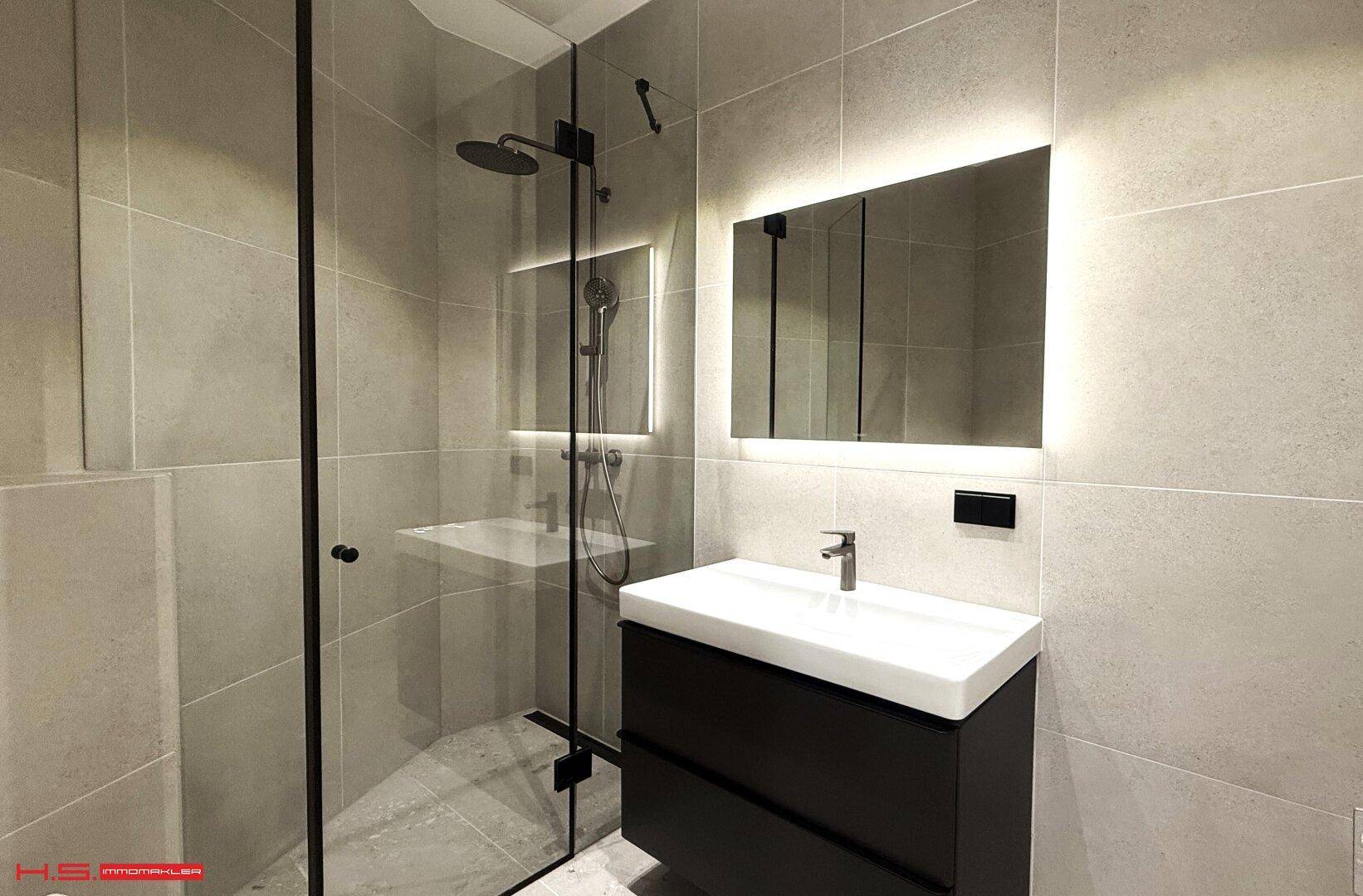 Elegantes Badezimmer mit großer begehbarer Dusche und modernem Waschtisch.