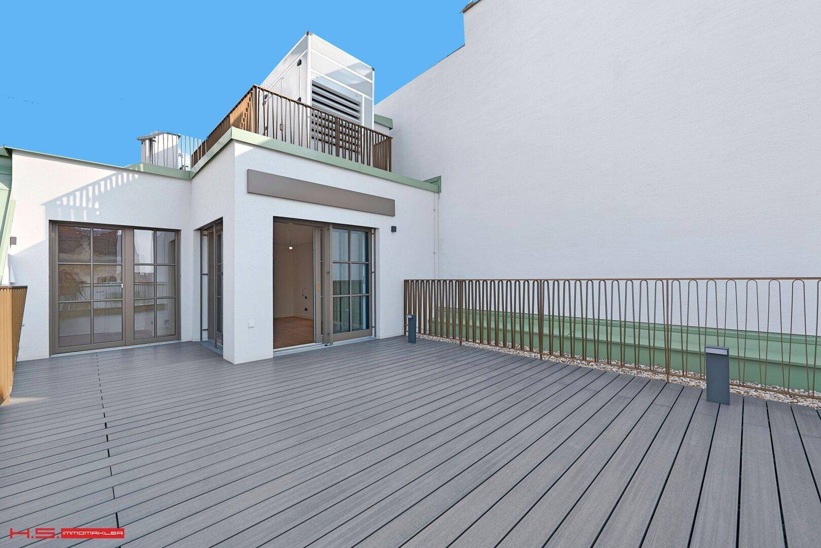 Weitläufige Dachterrasse mit Holzboden und mehreren Zugängen zu den Wohnbereichen.