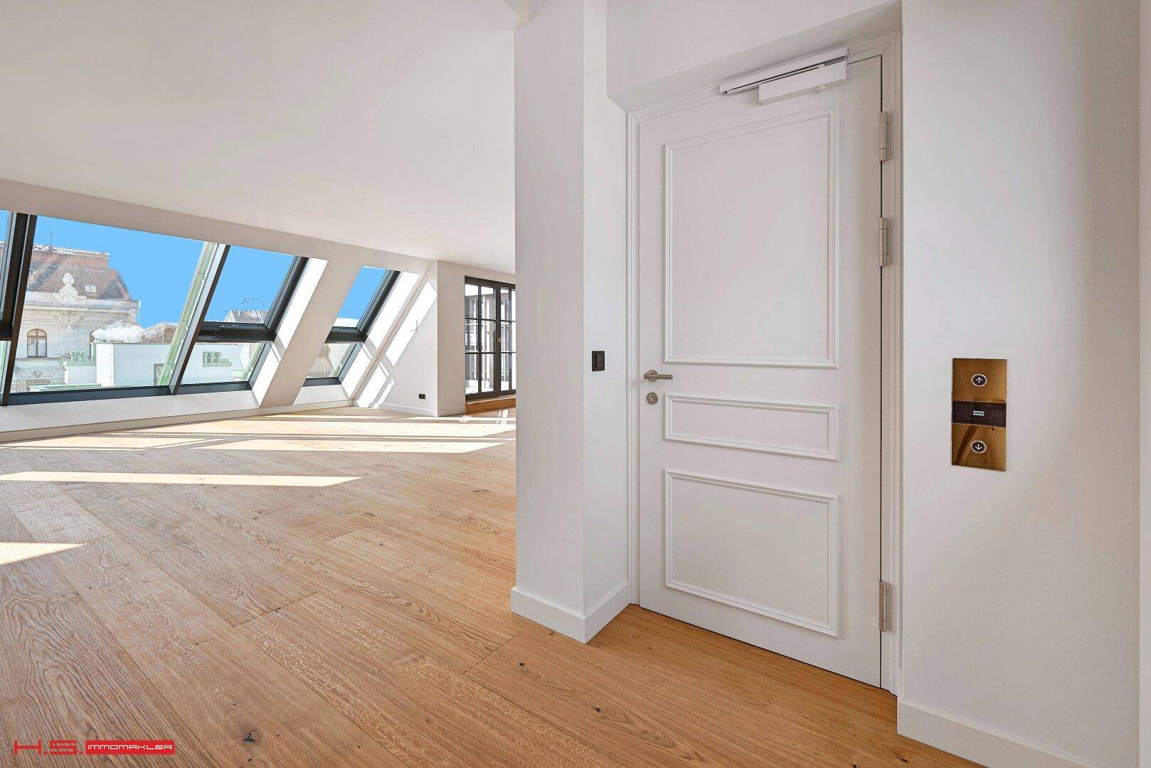 Eingangsbereich mit einer eleganten weißen Tür, die in einen hellen Raum mit Holzboden führt.