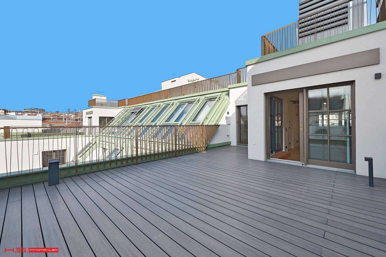 Große Dachterrasse mit Holzboden und Zugang zu den Innenräumen, umgeben von moderner Architektur.
