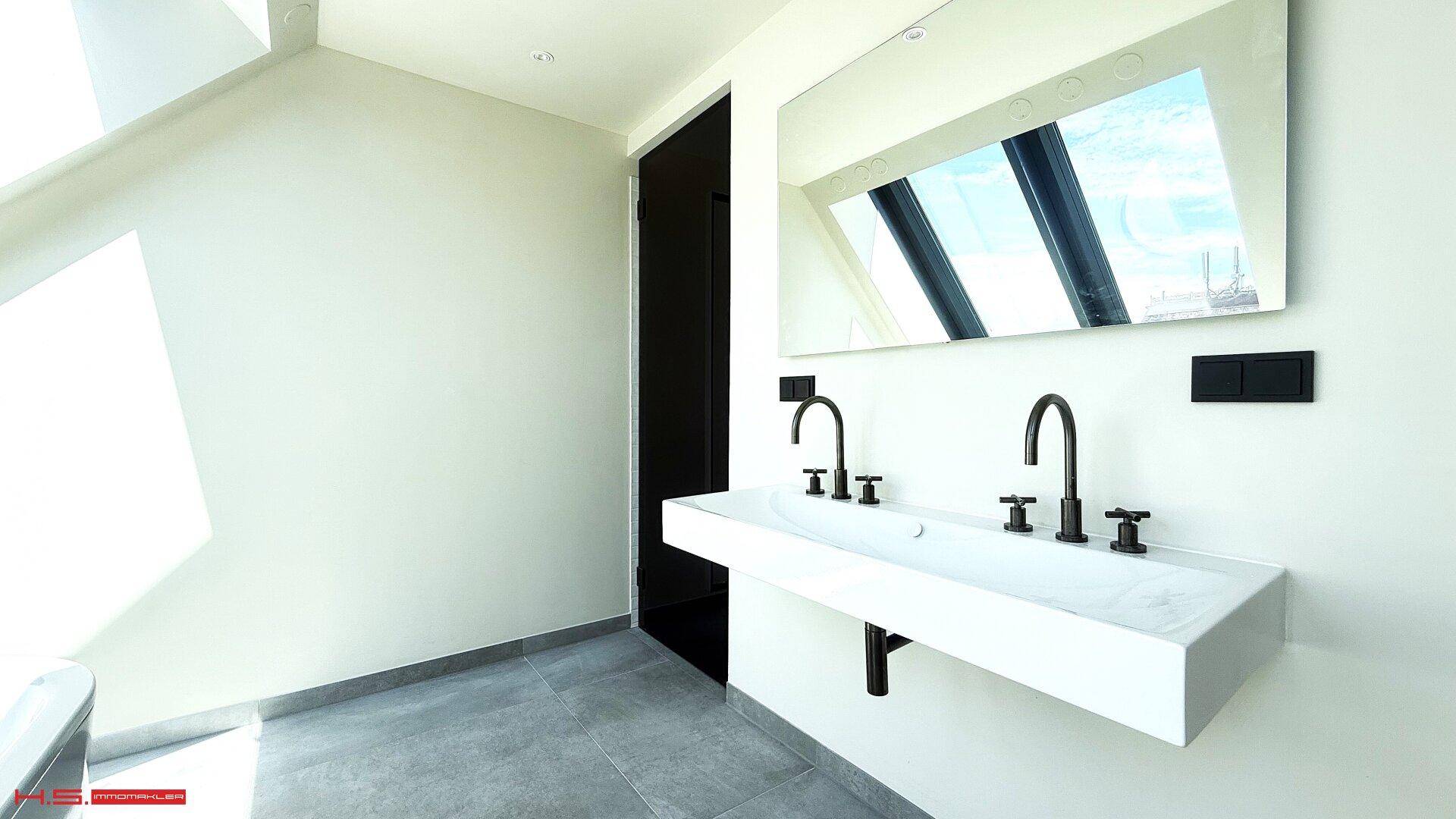 Modernes Badezimmer mit Doppelwaschbecken, großem Spiegel und grauen Fliesen, minimalistisch gestaltet.