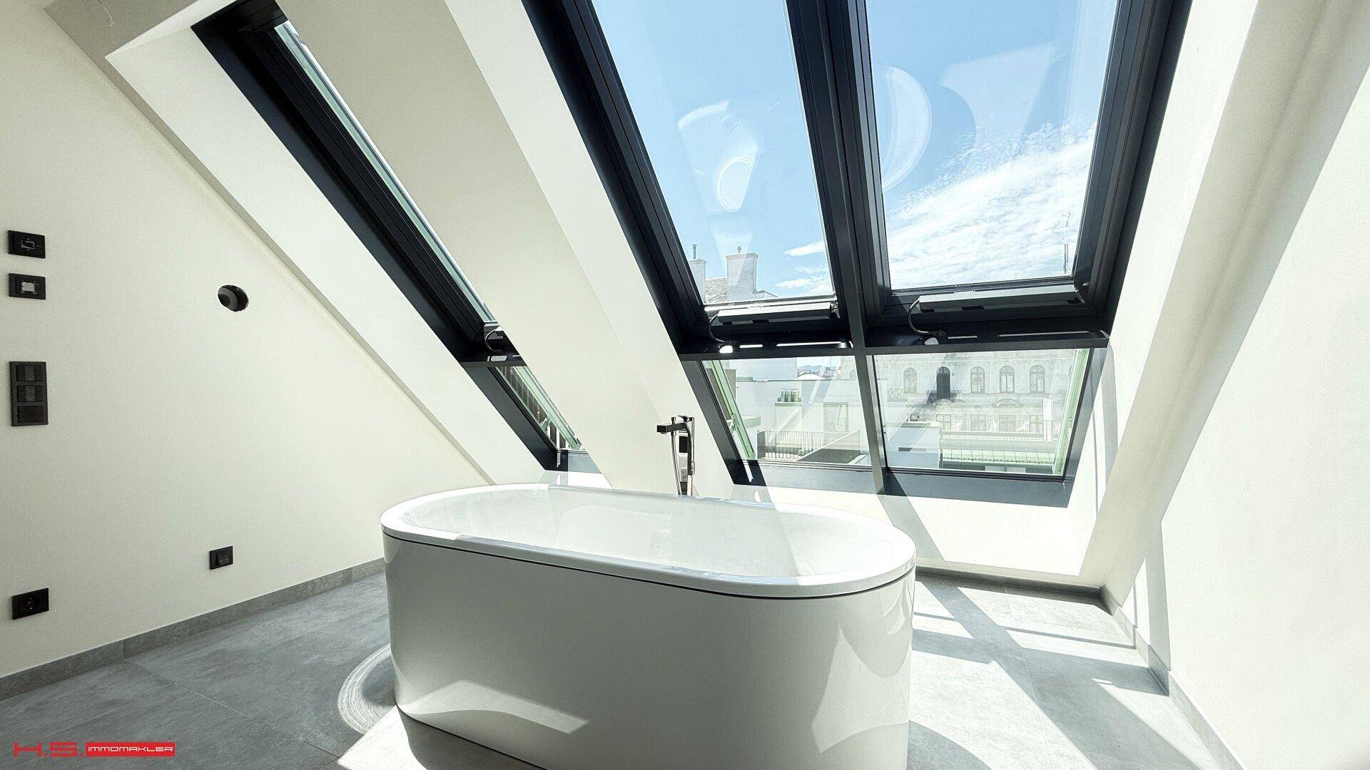 Geräumiges Badezimmer mit freistehender Badewanne und schrägen Dachfenstern, die den Raum erhellen.