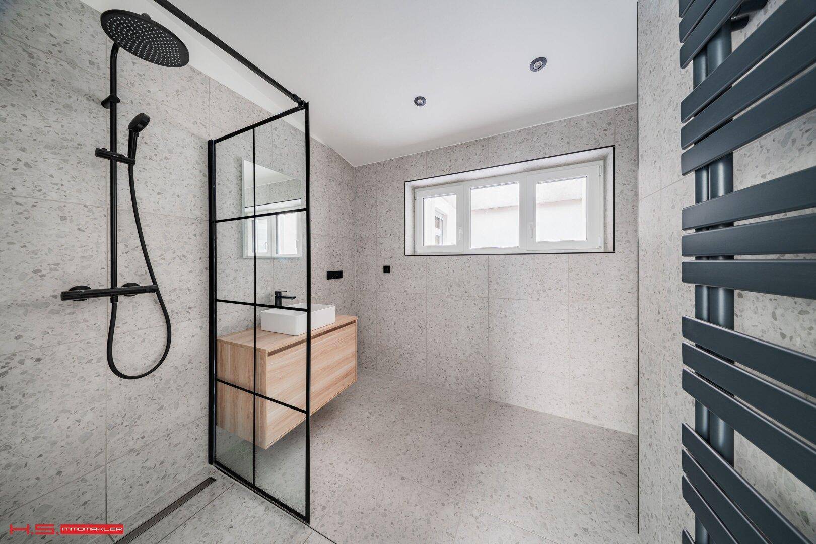 Modernes Badezimmer mit begehbarer Dusche, Regendusche und beheiztem Handtuchhalter.