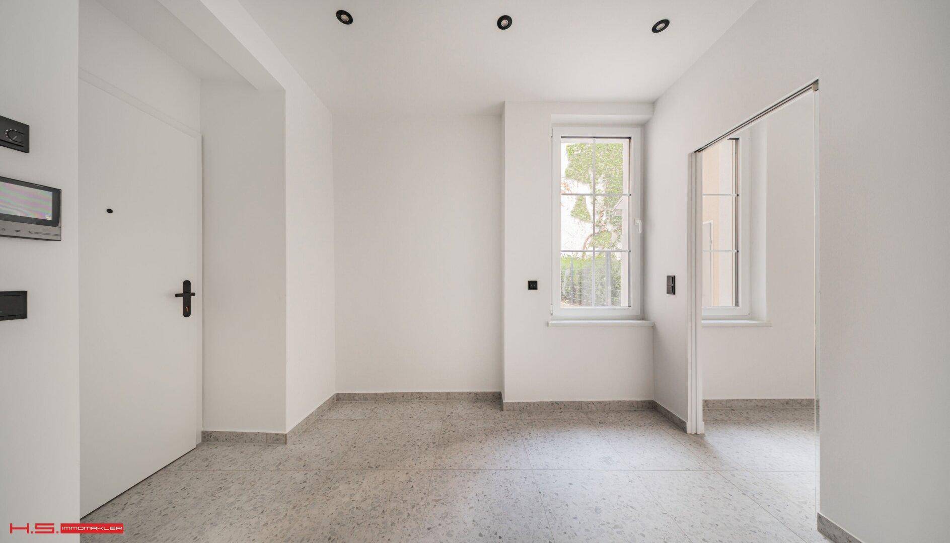 Heller Eingangsbereich mit modernen Fliesen und einem Fenster für natürliches Licht.