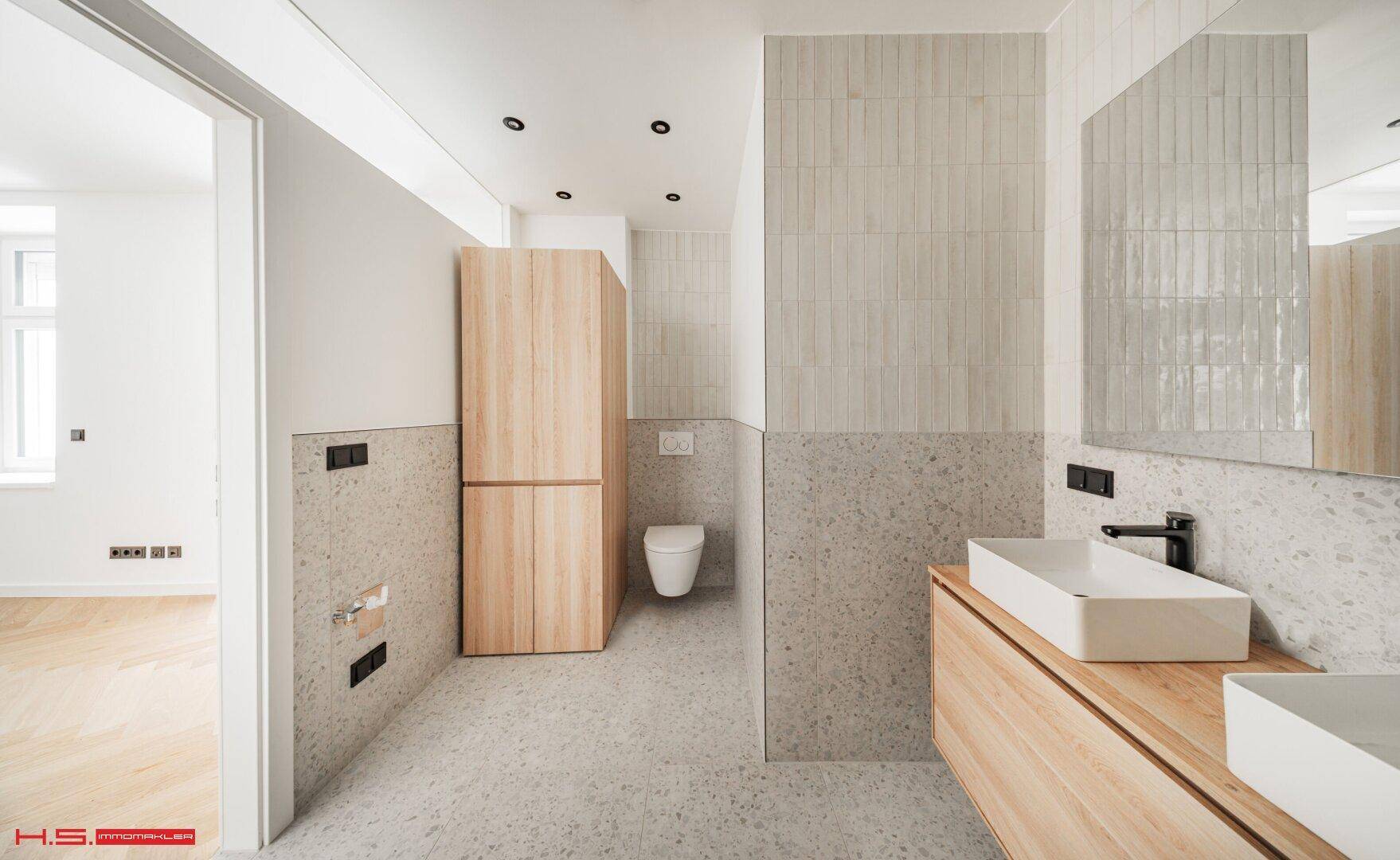 Modernes Badezimmer mit Doppelwaschbecken, Holzmöbeln und hellgrauen Fliesen.