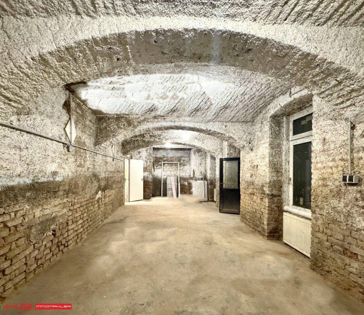 Historischer Kellerraum mit Gewölbedecken und unverputzten Ziegelwänden.