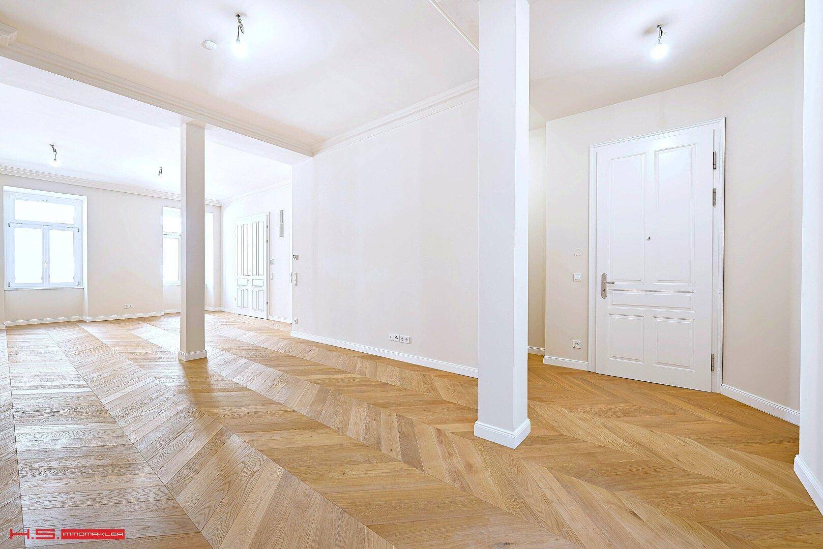 Heller, offener Raum mit Fischgrätparkett und hohen Türen, ideal für flexible Gestaltung.